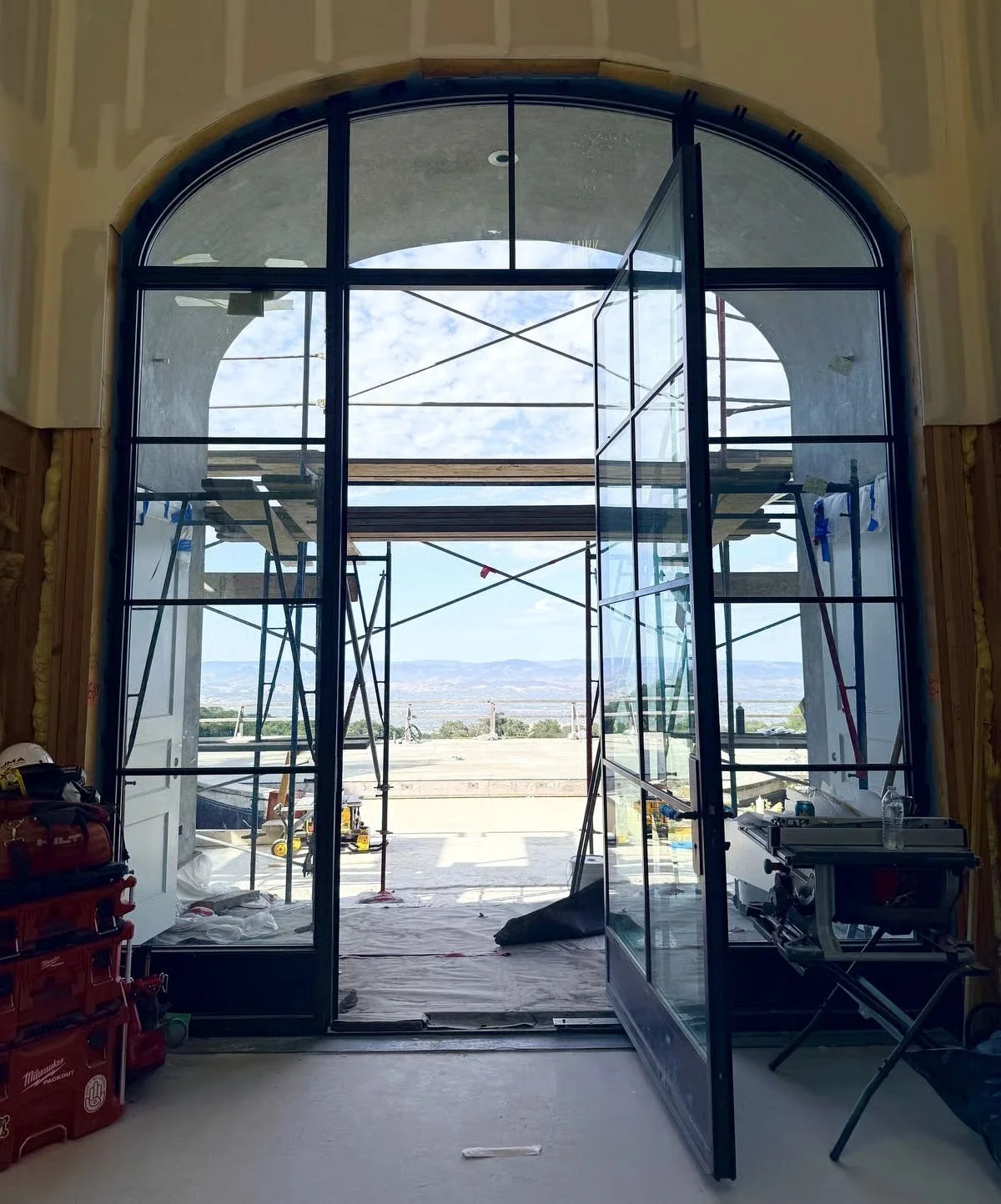 Arched steel window under construction with view to the grounds, project in progress