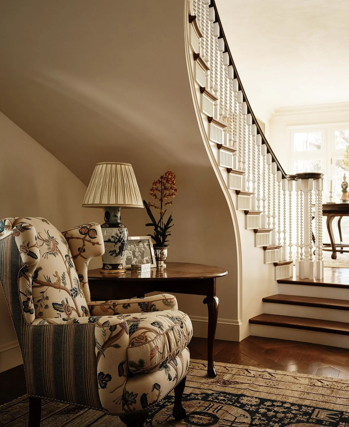 Stair hall landing with floral armchair beside curved staircase, Hillsborough Estate