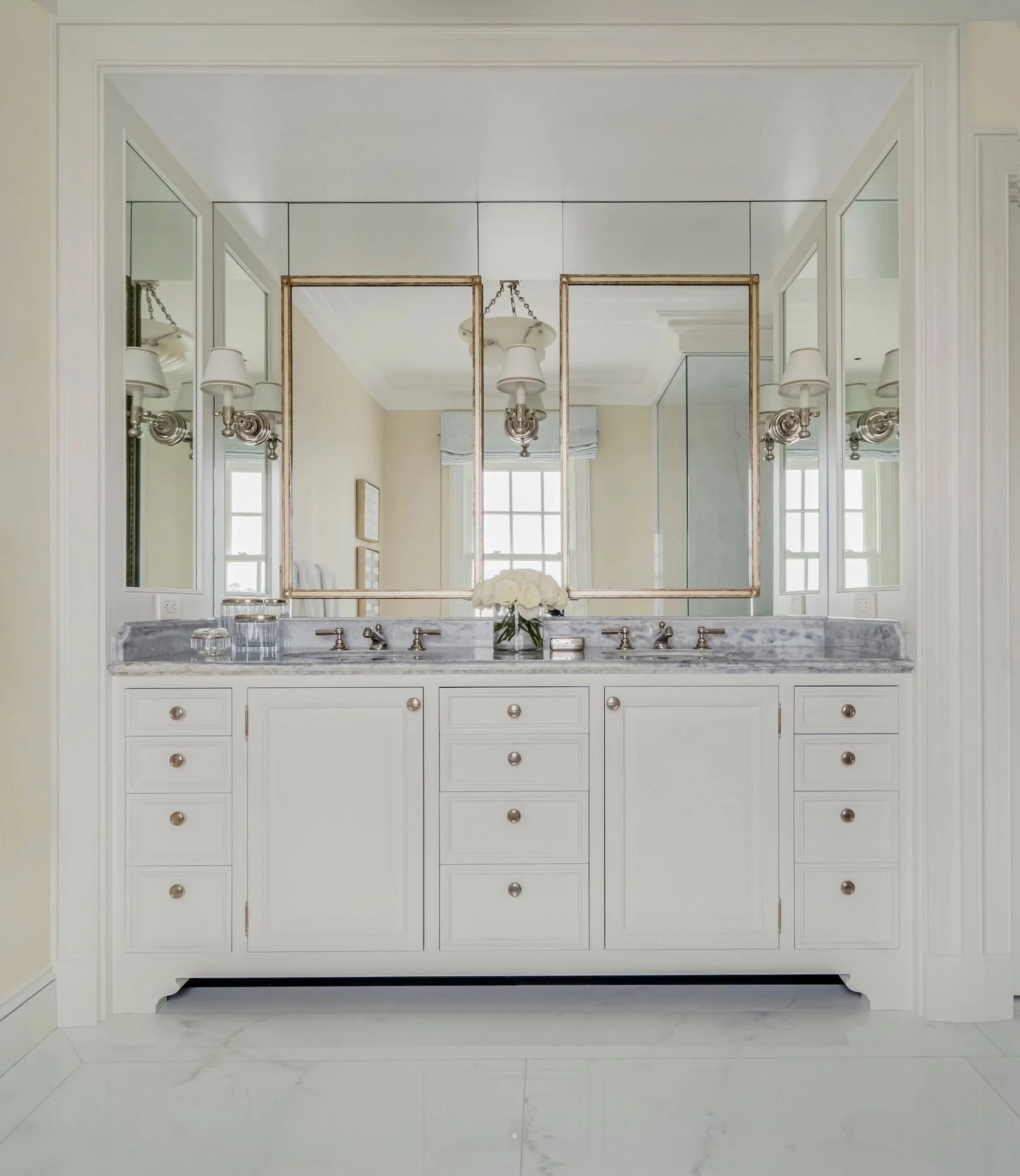 White marble bathroom with double vanity and mirrored wall