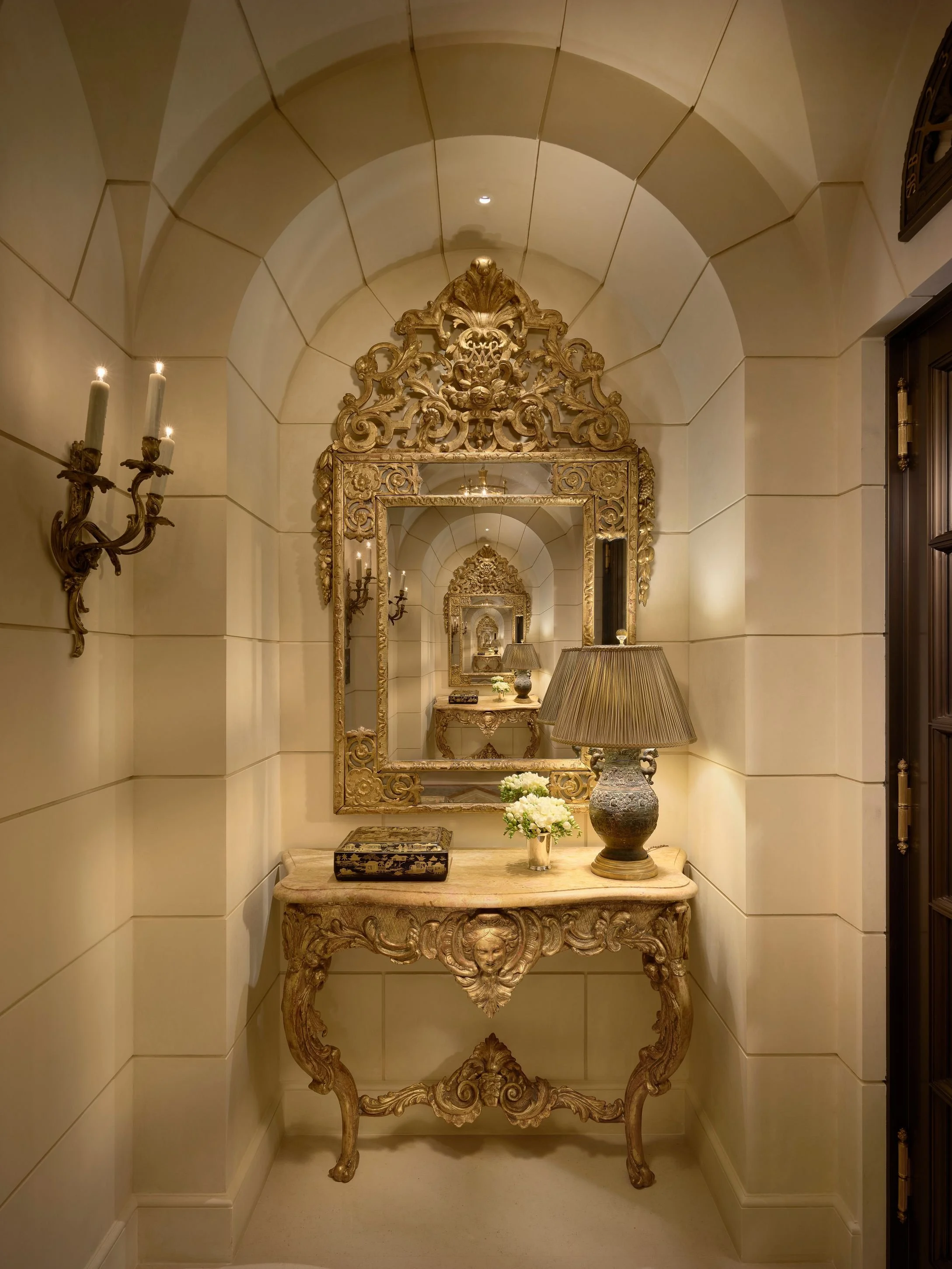 Arched stone niche with gilt console, ornate mirror, and candle sconce, Classic French Apartment