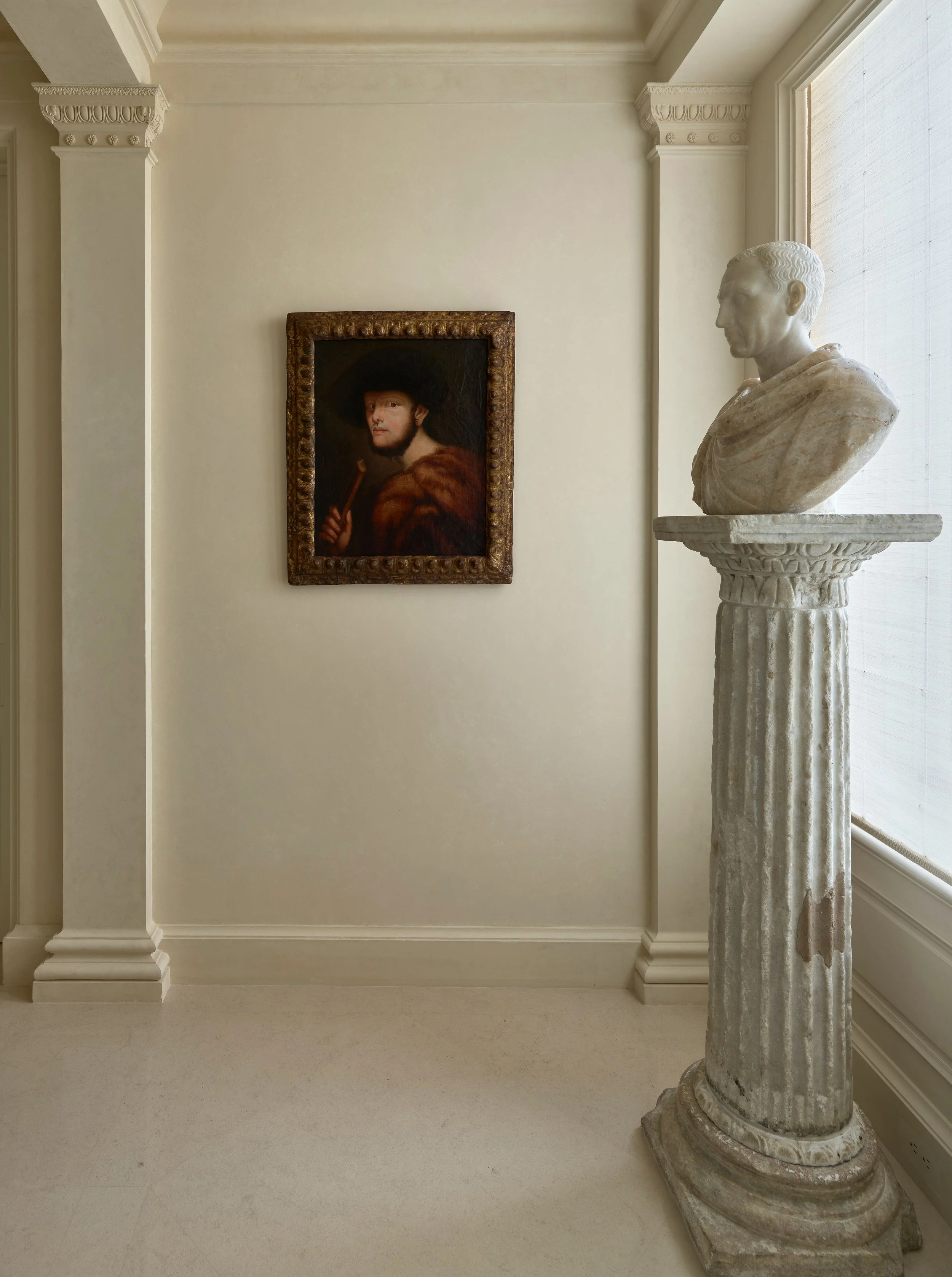 Hallway vignette with portrait painting and marble bust on a column