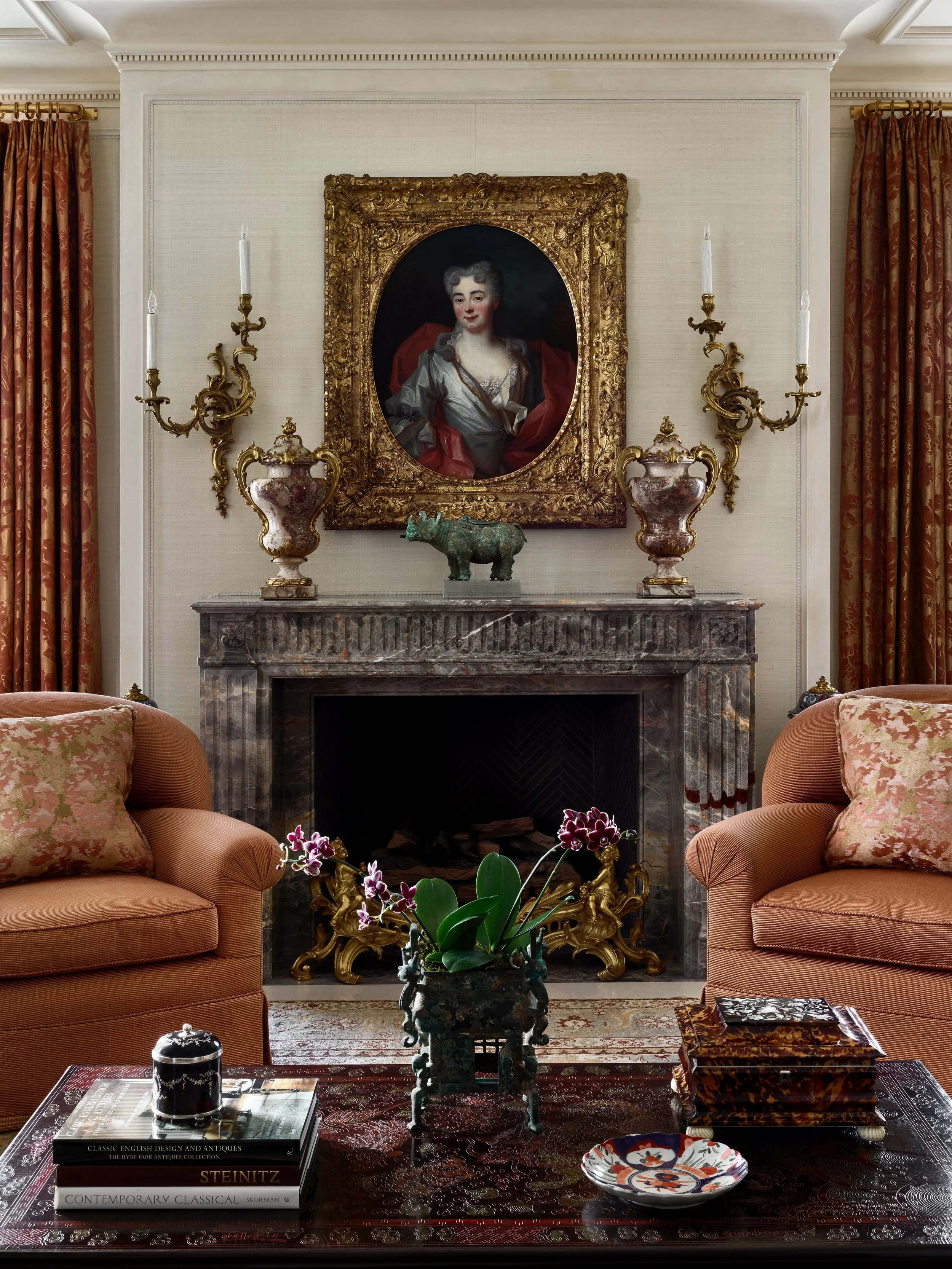 Living room fireplace with marble mantel, portrait painting, and striped armchairs