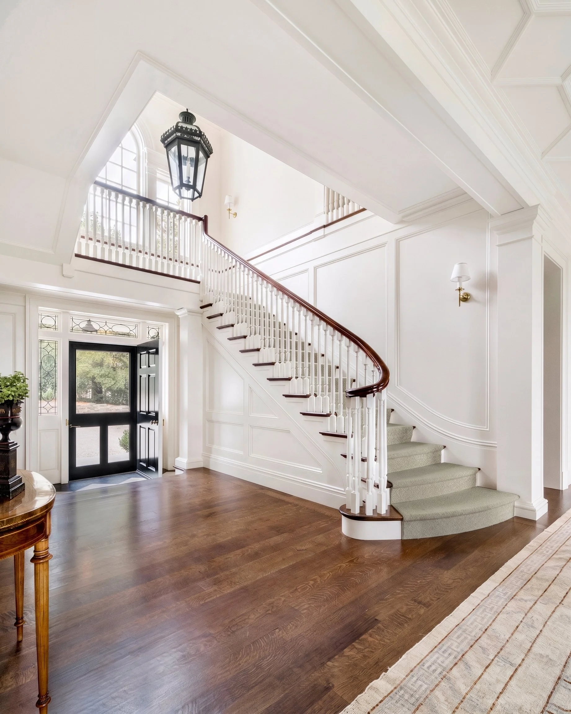 Stair hall with curved staircase, hanging lantern, and French doors