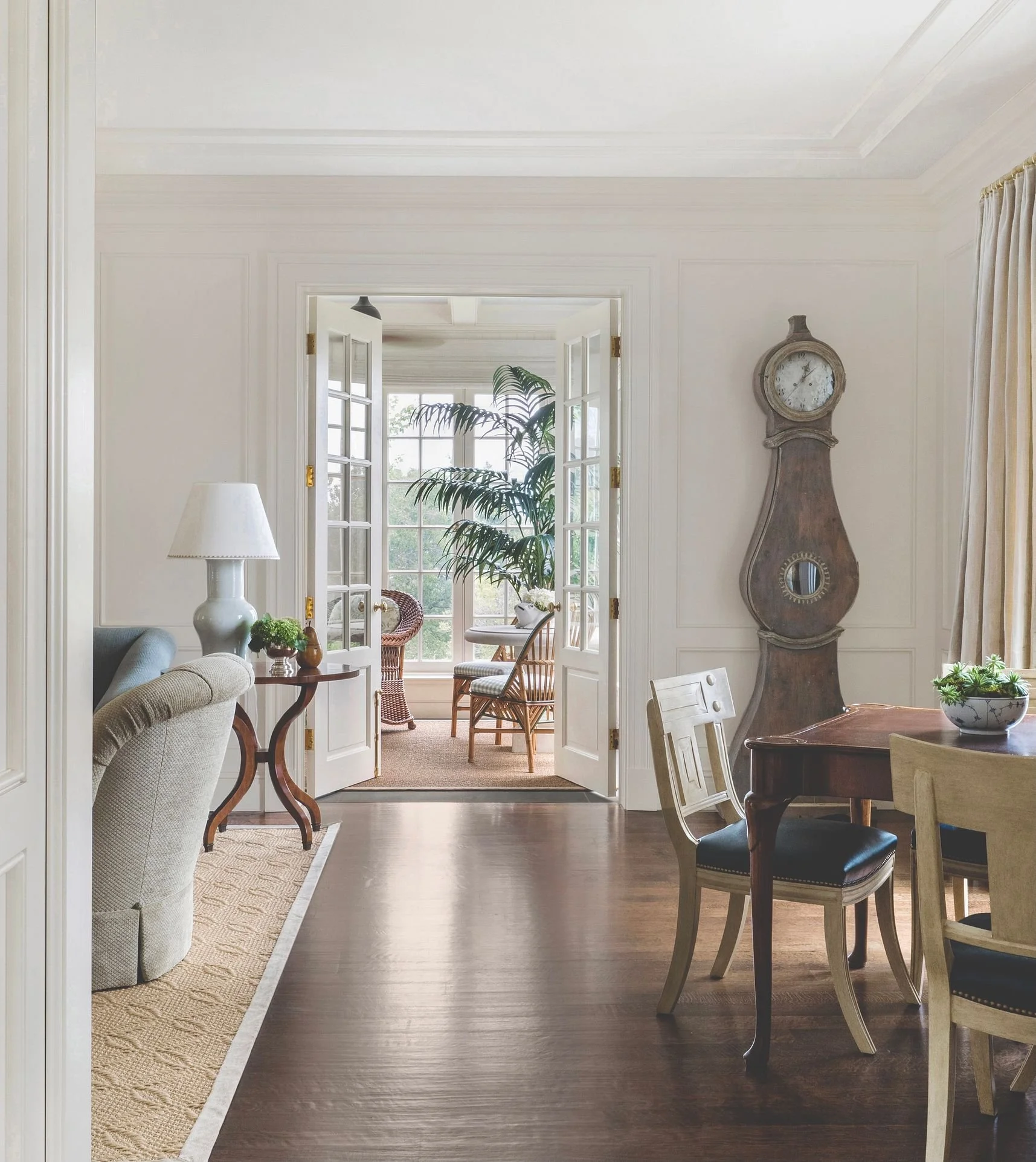 Hallway with antique tall case clock and view into the sunroom
