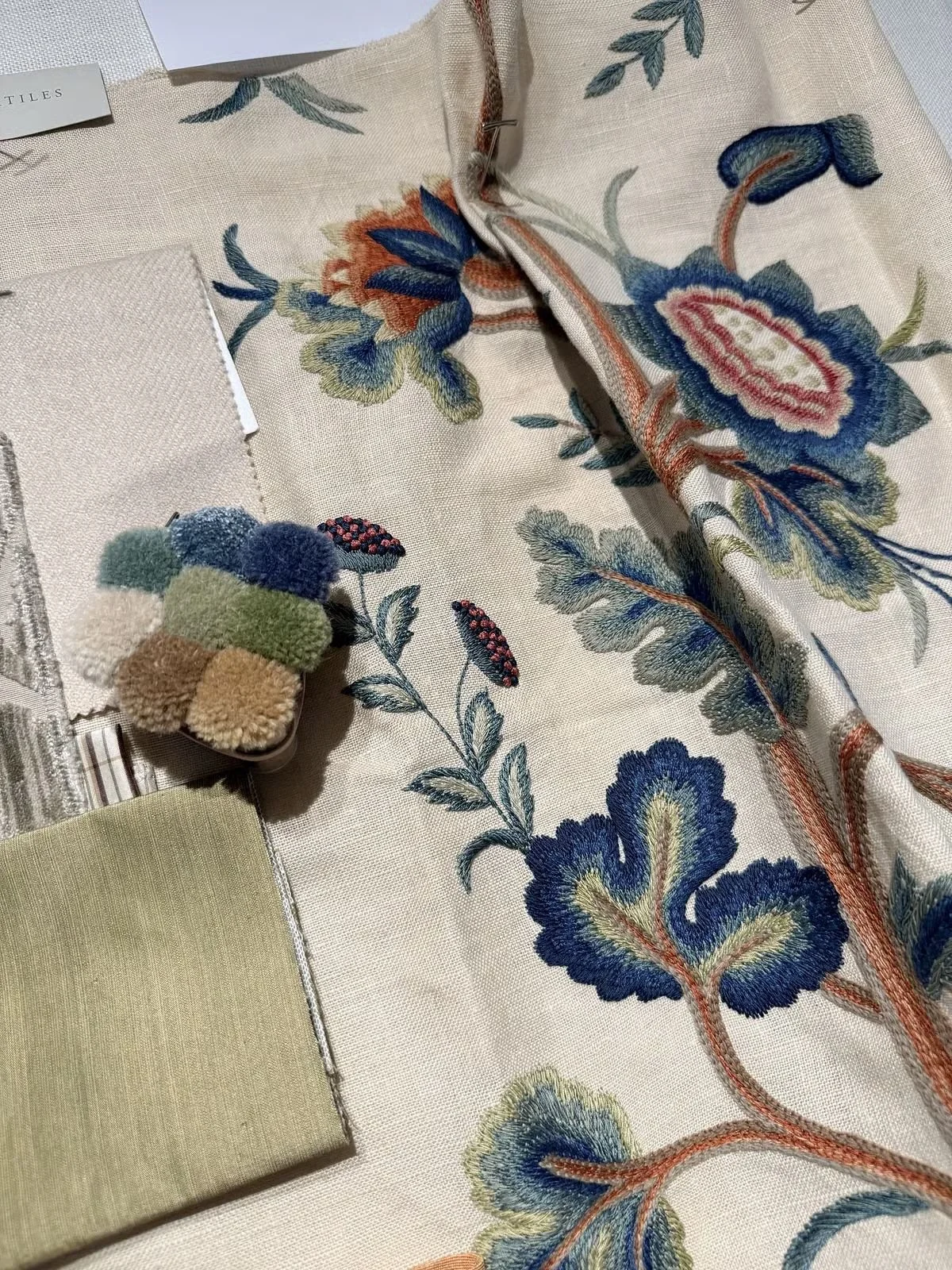 Embroidered floral textile layered over a woven fabric sample, project in progress