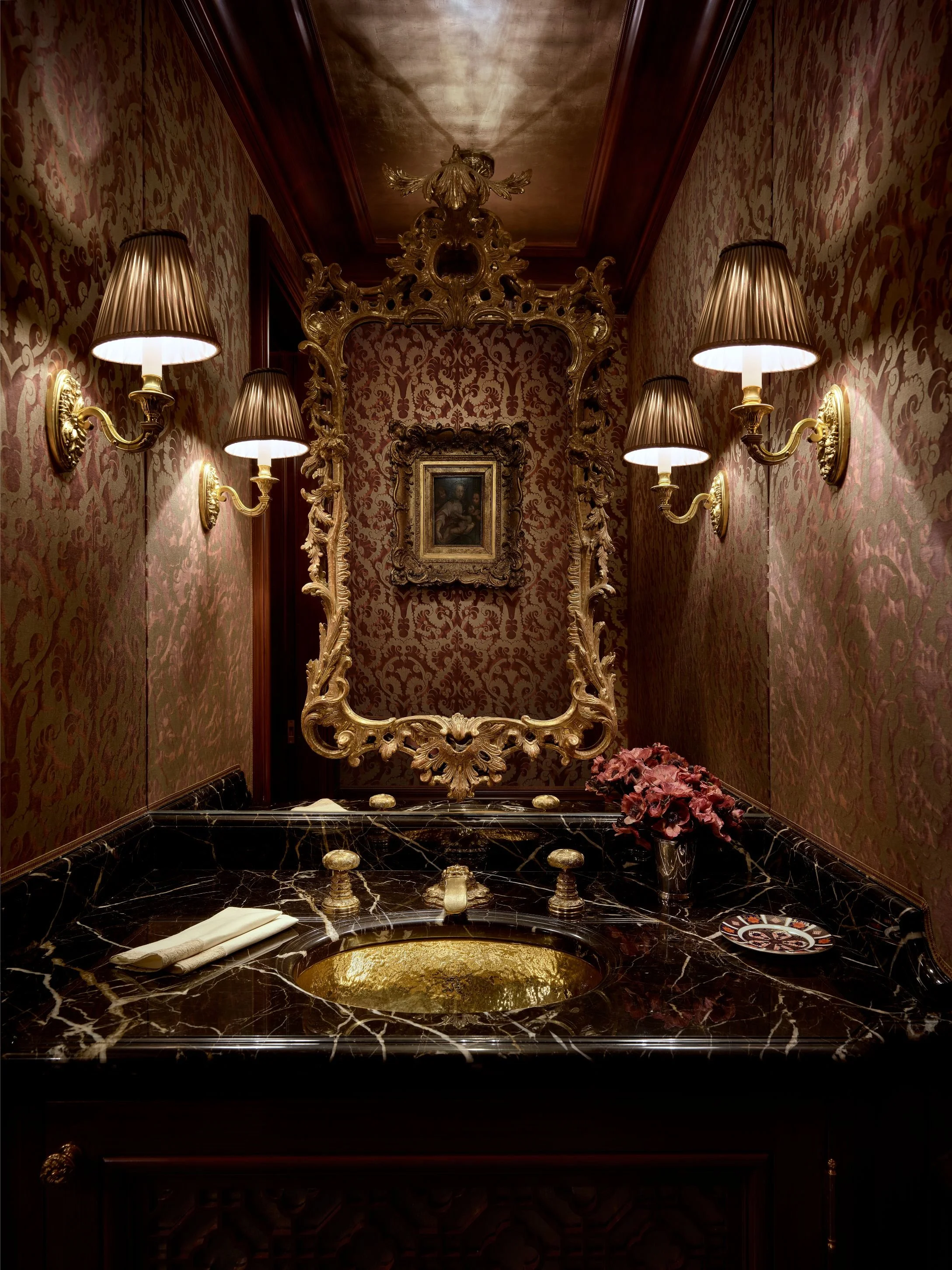 Powder room with ornate gilt mirror, sconces, and black marble vanity