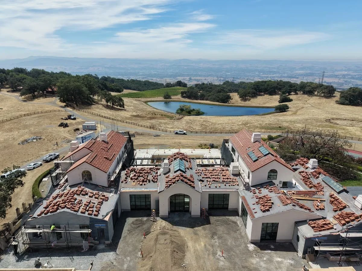 Aerial view of a hillside residence under construction with pool and ocean view