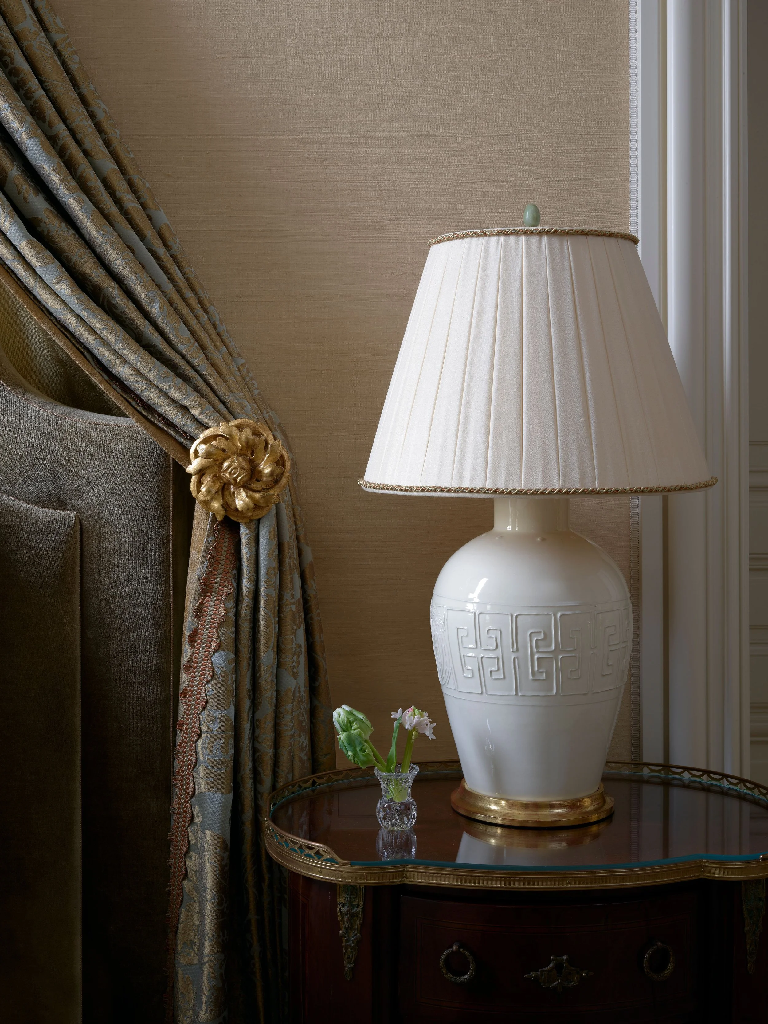Detail of white ceramic lamp beside canopy drapery