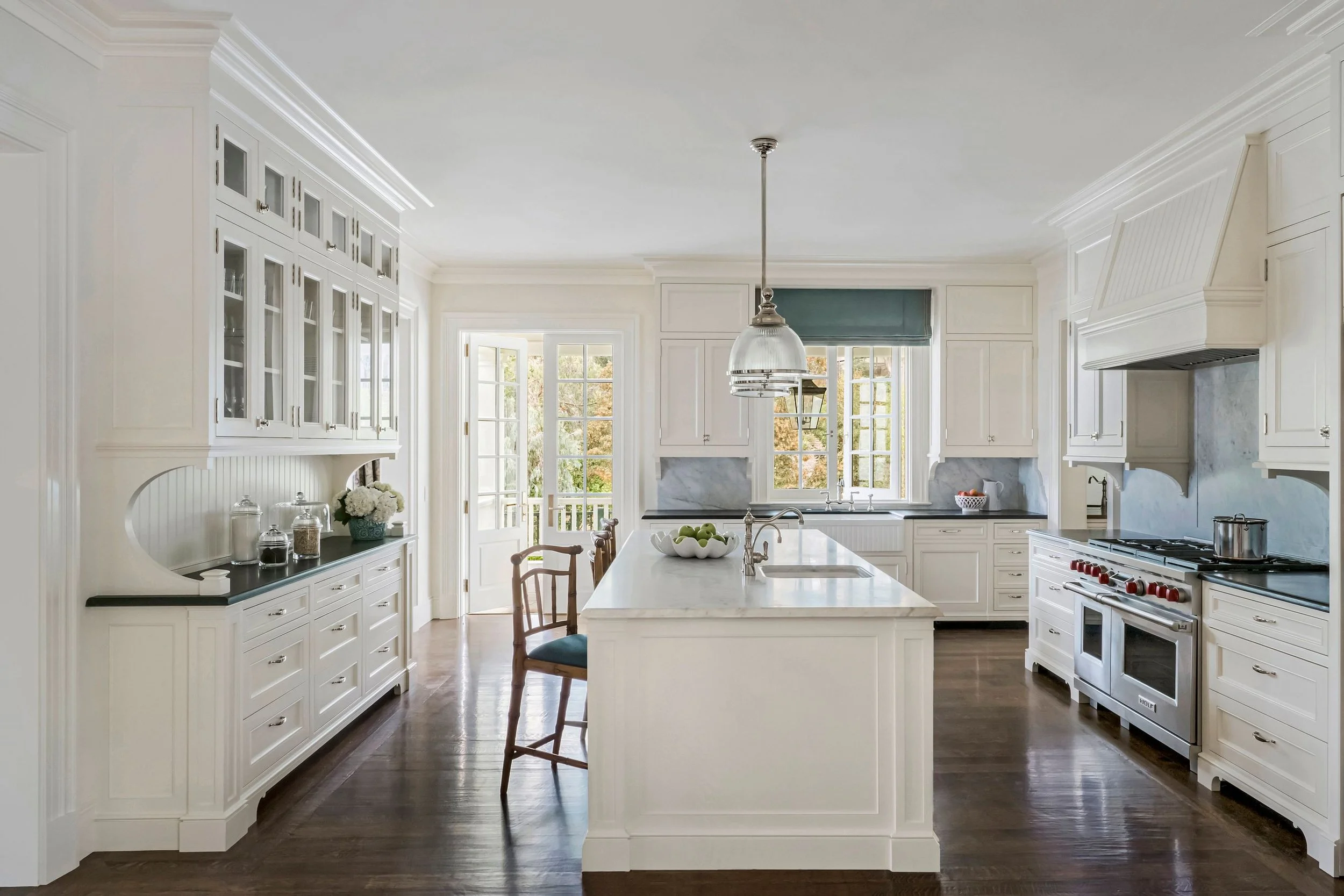 White kitchen with marble island, glass-front cabinets, and counter stools, East Coast Georgian