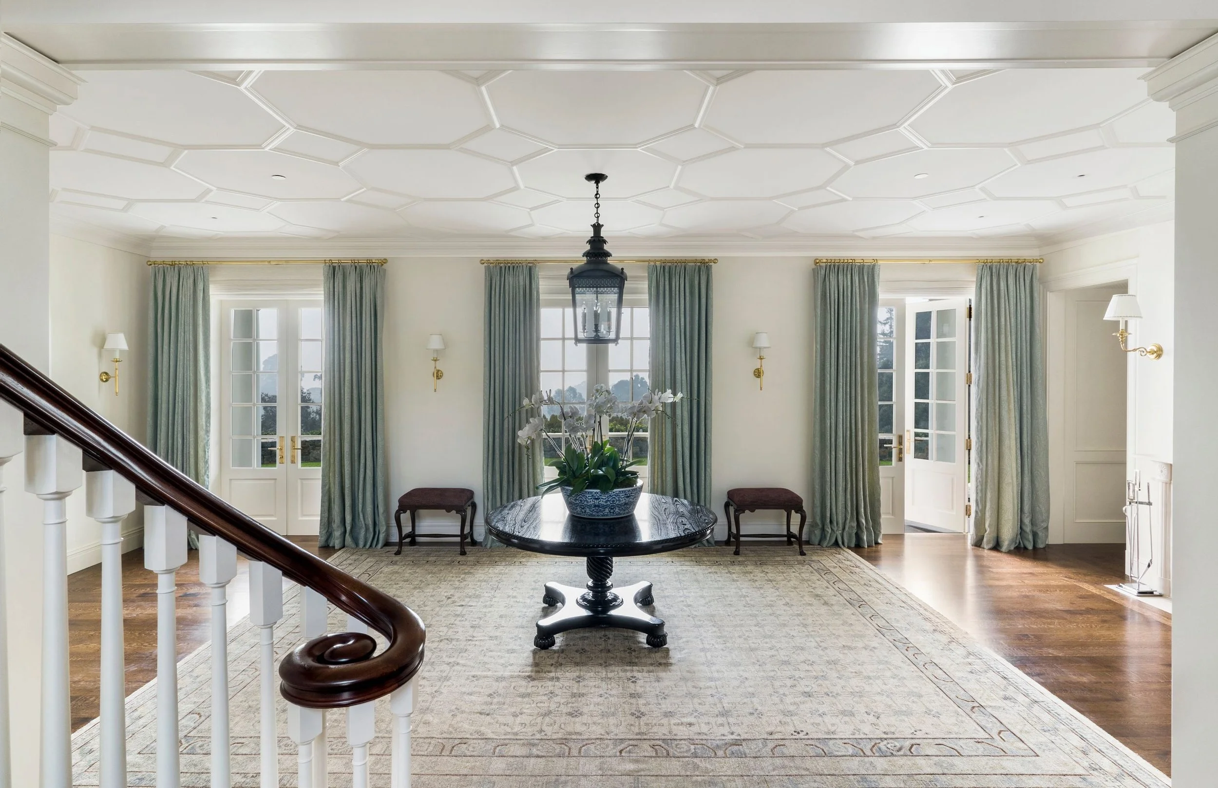 Entry hall with hexagonal ceiling molding, round pedestal table, and curved stair rail, East Coast Georgian
