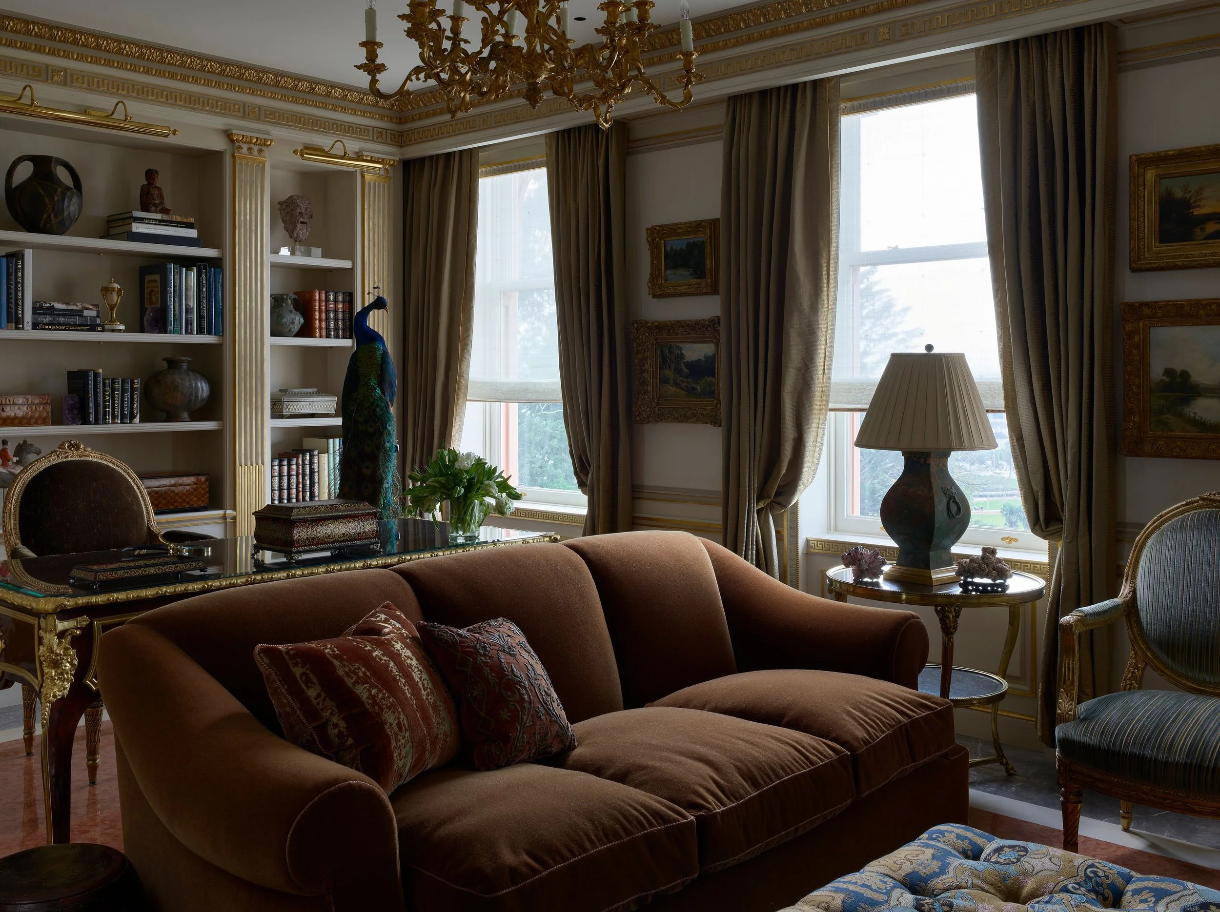 Library with brown velvet sofa, built-in bookshelves, and silk drapery