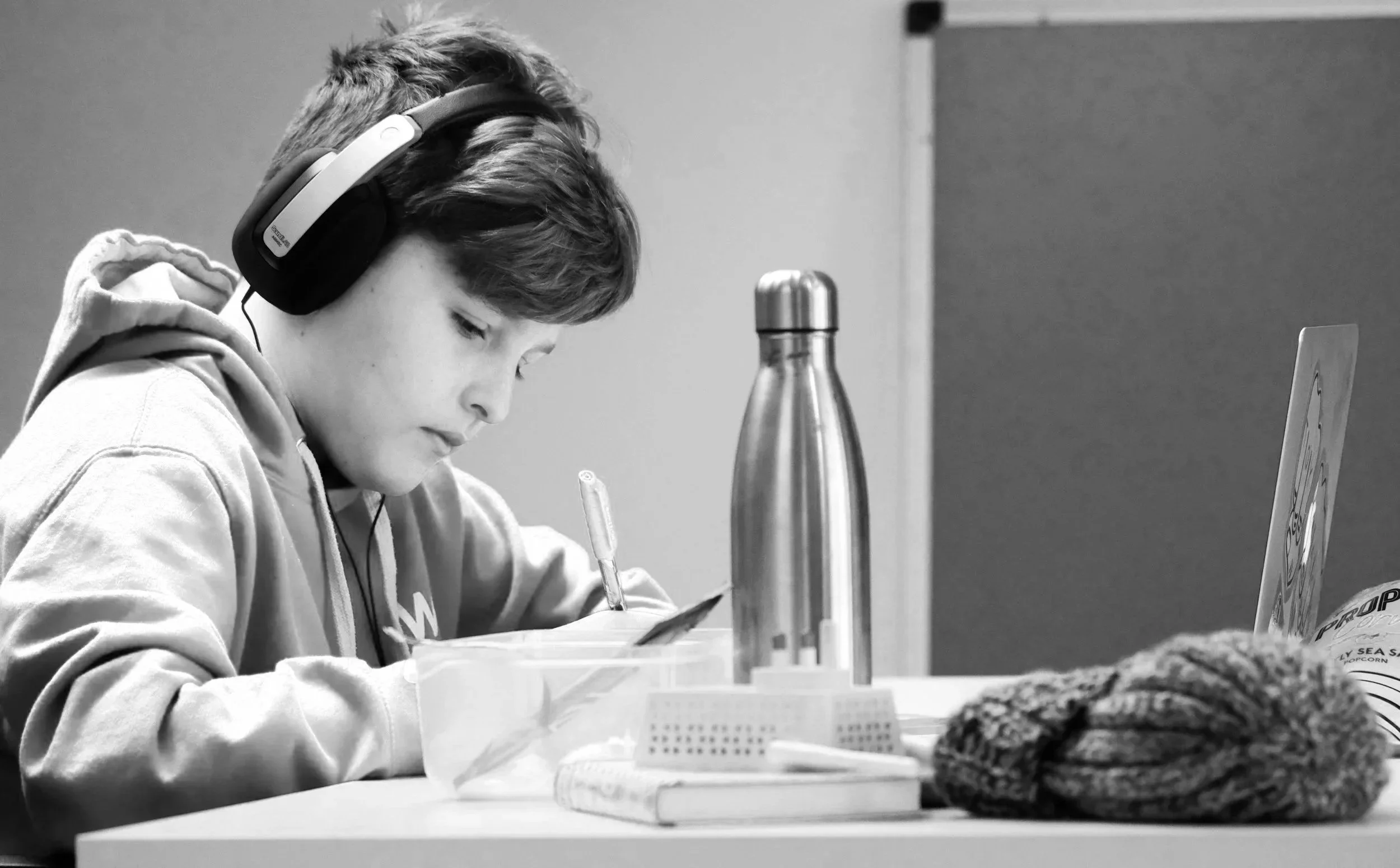 Child wearing headphones and concentrating on writing, reflecting how everyday tasks can require extra effort for children with ADHD, even when they're trying their best.