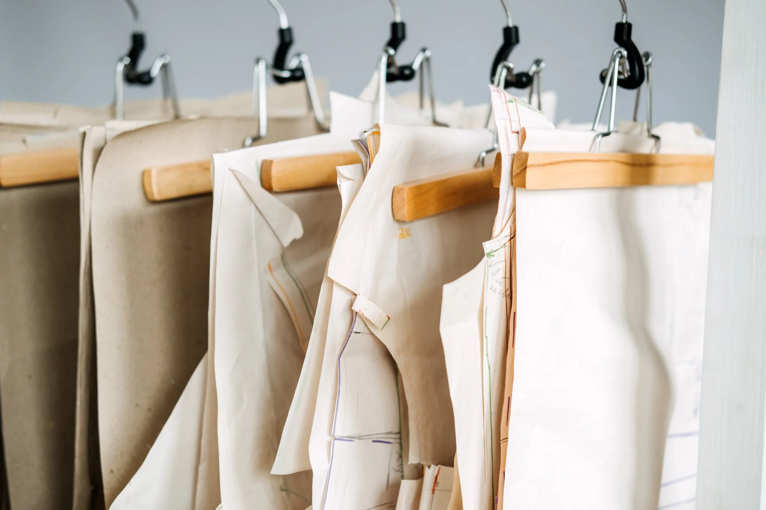 Multiple paper bags with wooden handles hanging on metal hooks on a wall.