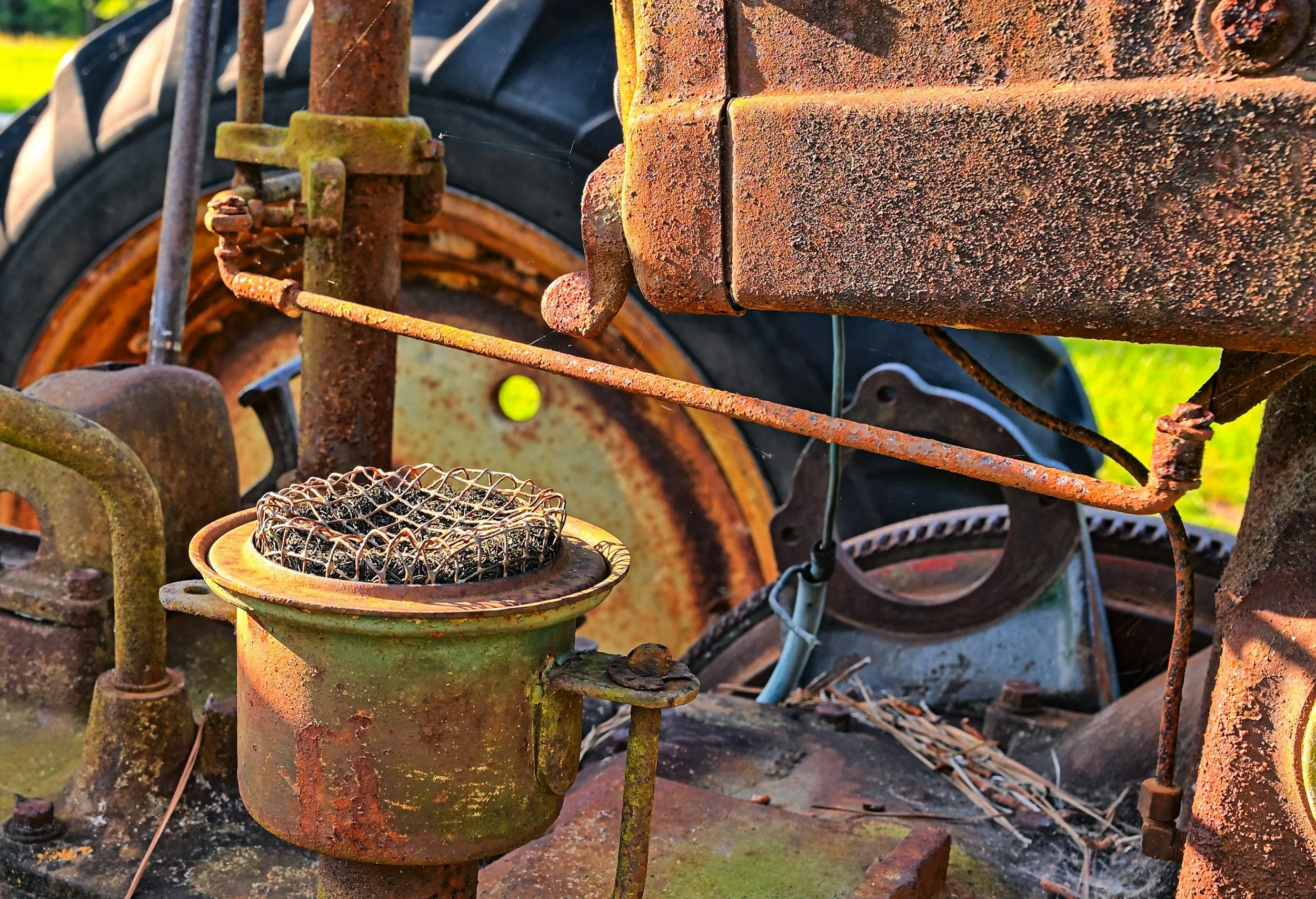 Close-up of an old, rusted tractor with a worn tire in the background.