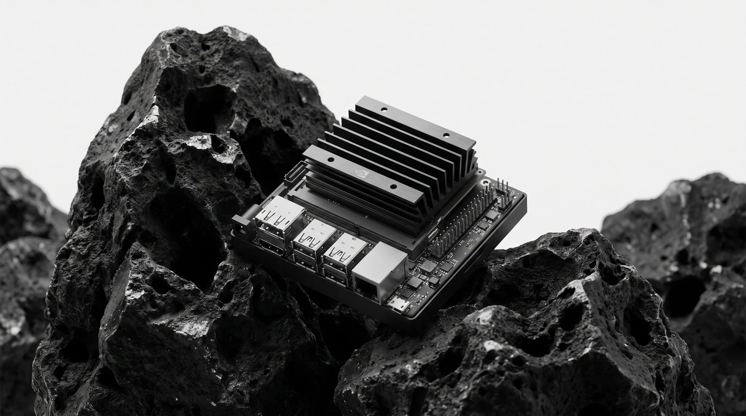 A computer motherboard with a heatsink placed on top, set among dark volcanic rocks, with a plain white background.