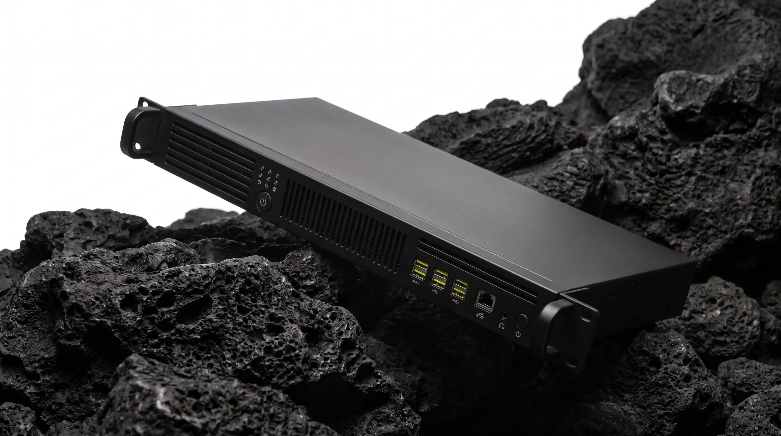 A black computer server with various ports and indicator lights is placed on rough, dark volcanic rocks.