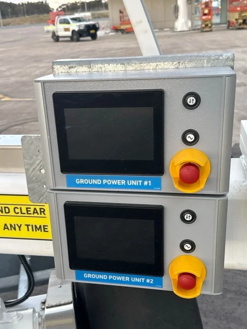 Electrical control panel of a Dynell System with two digital displays labeled 'Ground Power Unit #1' and 'Ground Power Unit #2,' each with yellow emergency stop buttons.