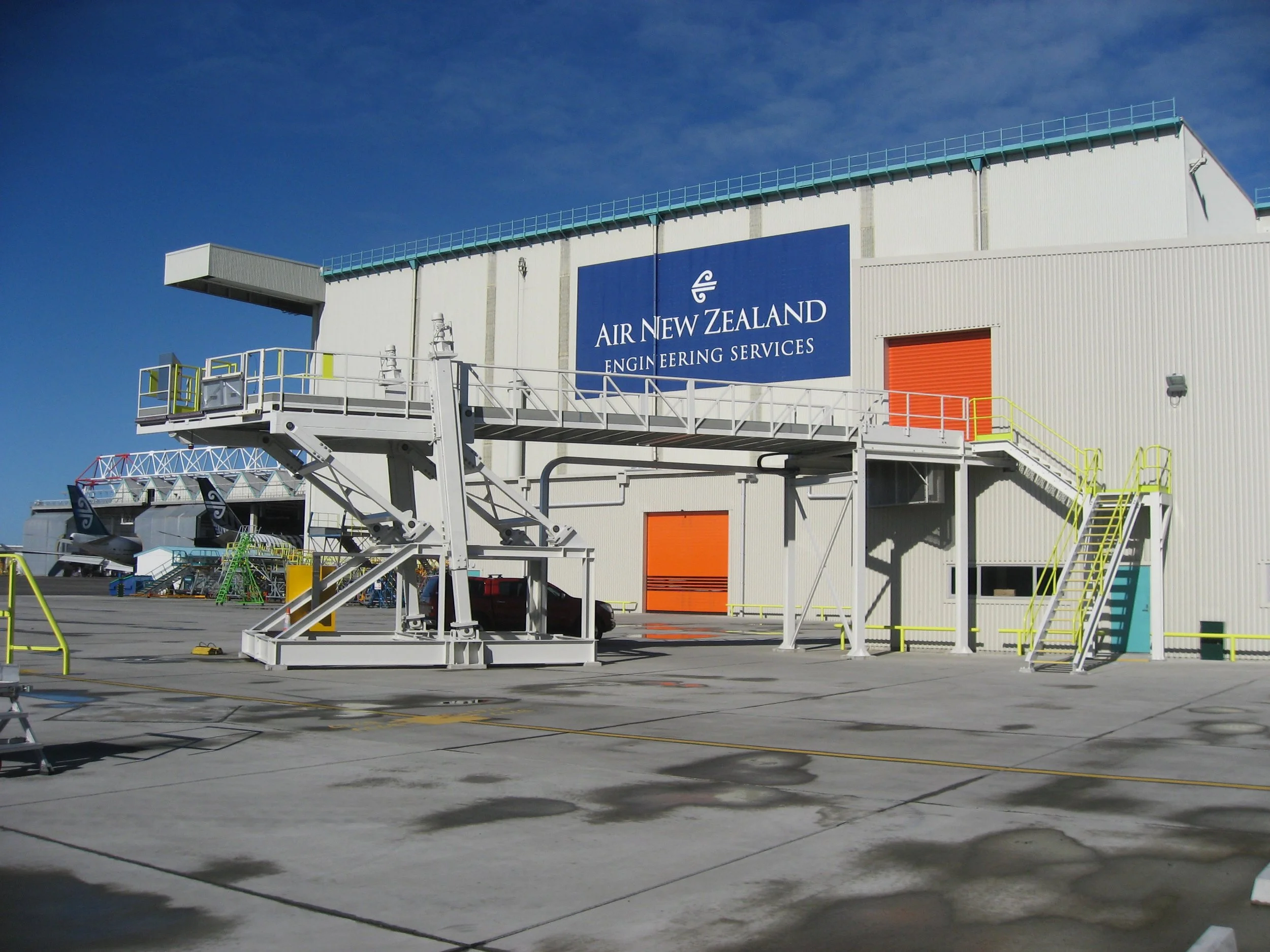 Airport access stairs and platform on the tarmac in front of an Air New Zealand building.