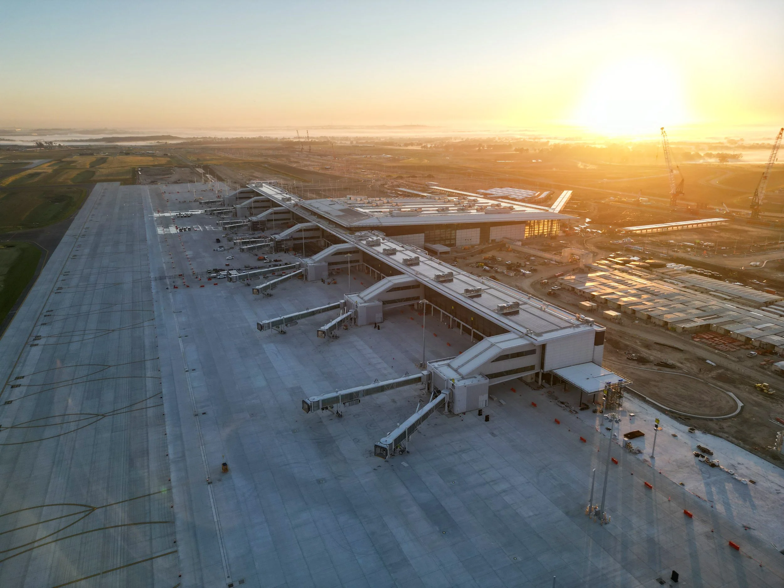 A drone image of Western Sydney International Airport at sunset shows several passenger boarding bridges designed by Airport Equipment.