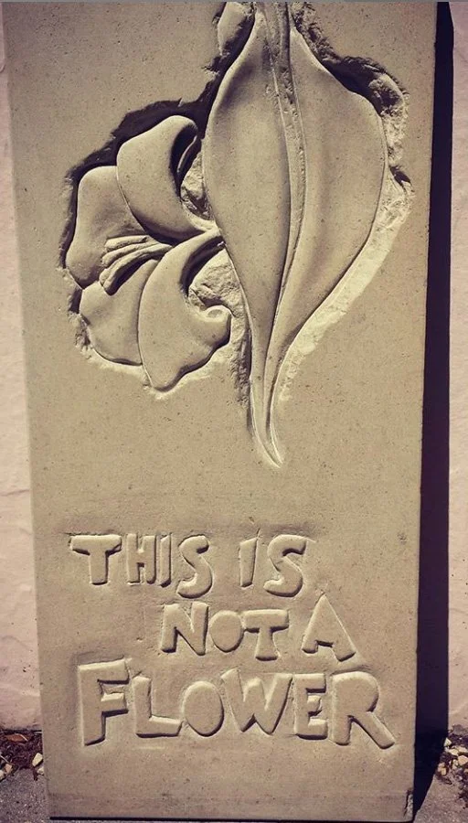 Stone light relief carving with a flower and the inscription "This is not a flower."  Tip of the hat to Magritte.