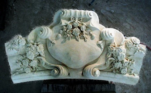 Ornate carved stone cartouche with floral and scroll details.