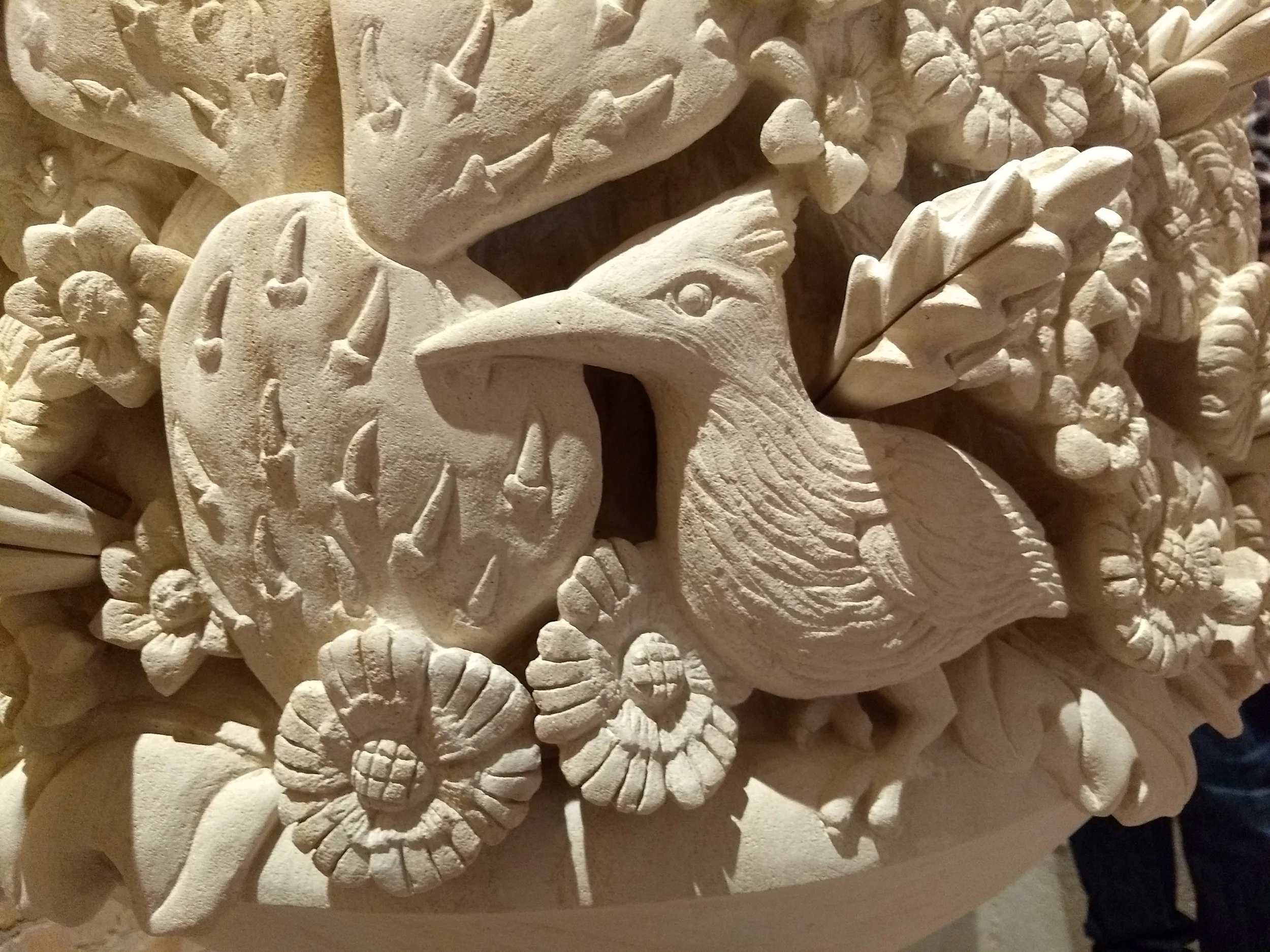 Close-up of an intricate carved stone relief featuring a chaparral and cactus