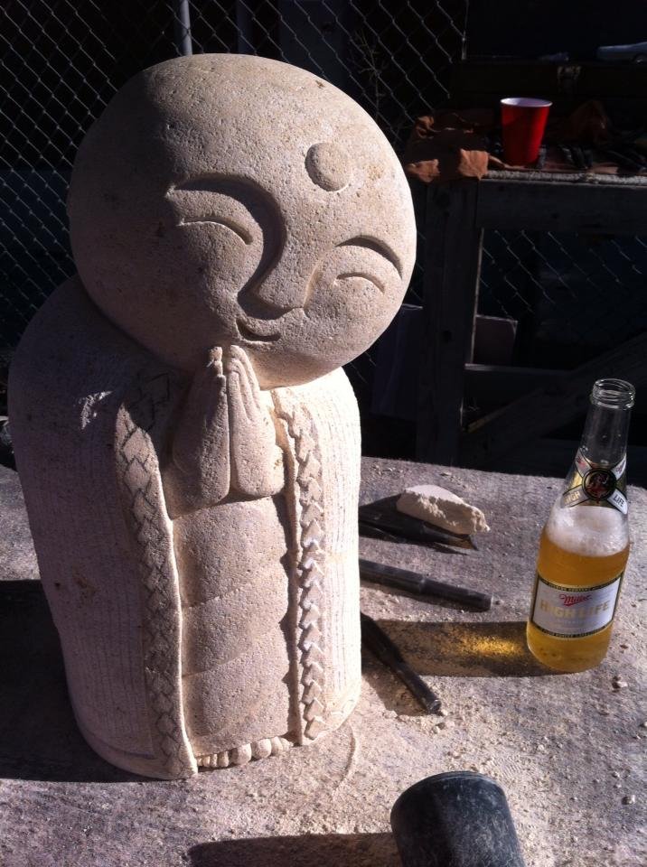 A stone sculpture of a smiling Jizo Bodhisattva