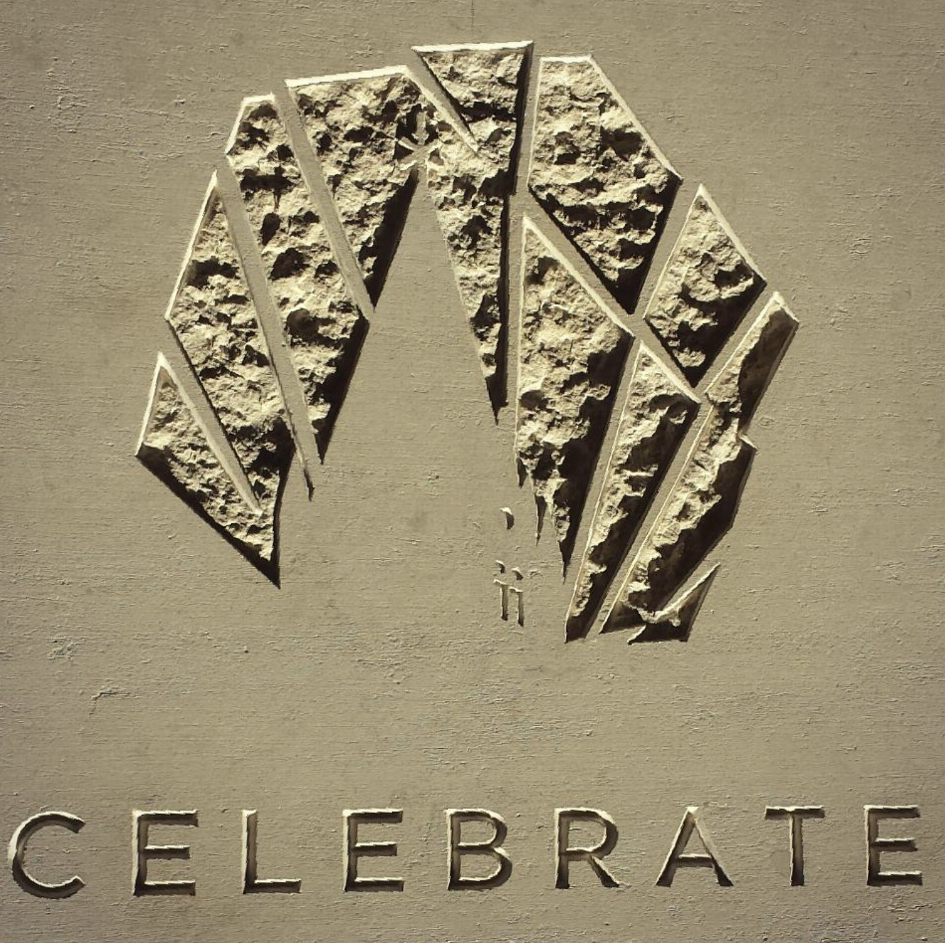 A logo with a stylized diamond-shaped emblem and the word 'CELEBRATE' underneath on a beige textured background.