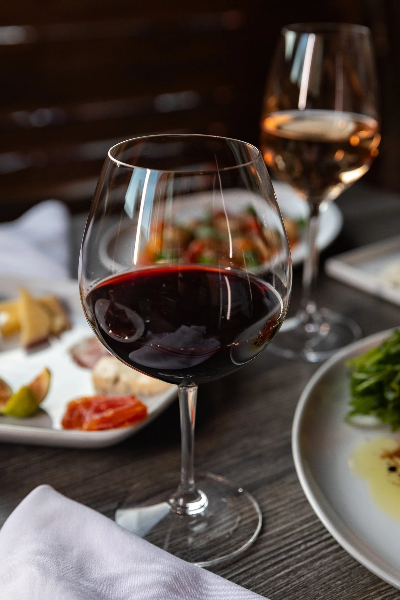 Glass of red wine with small plates at dinner at Bacchus Kitchen + Wine Bar in Pasadena