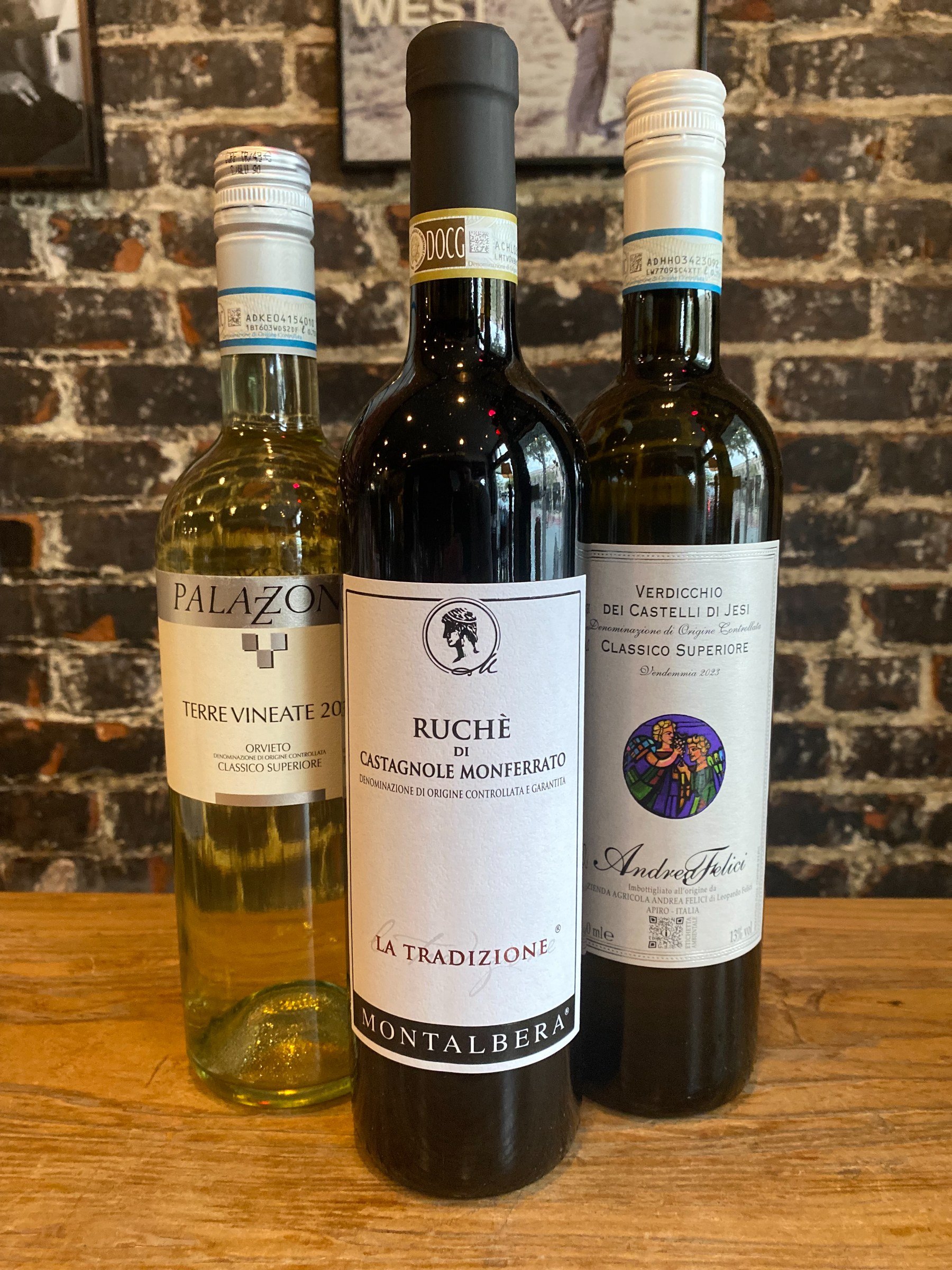 Three Bacchus Wine Club bottles on the bar against a brick wall