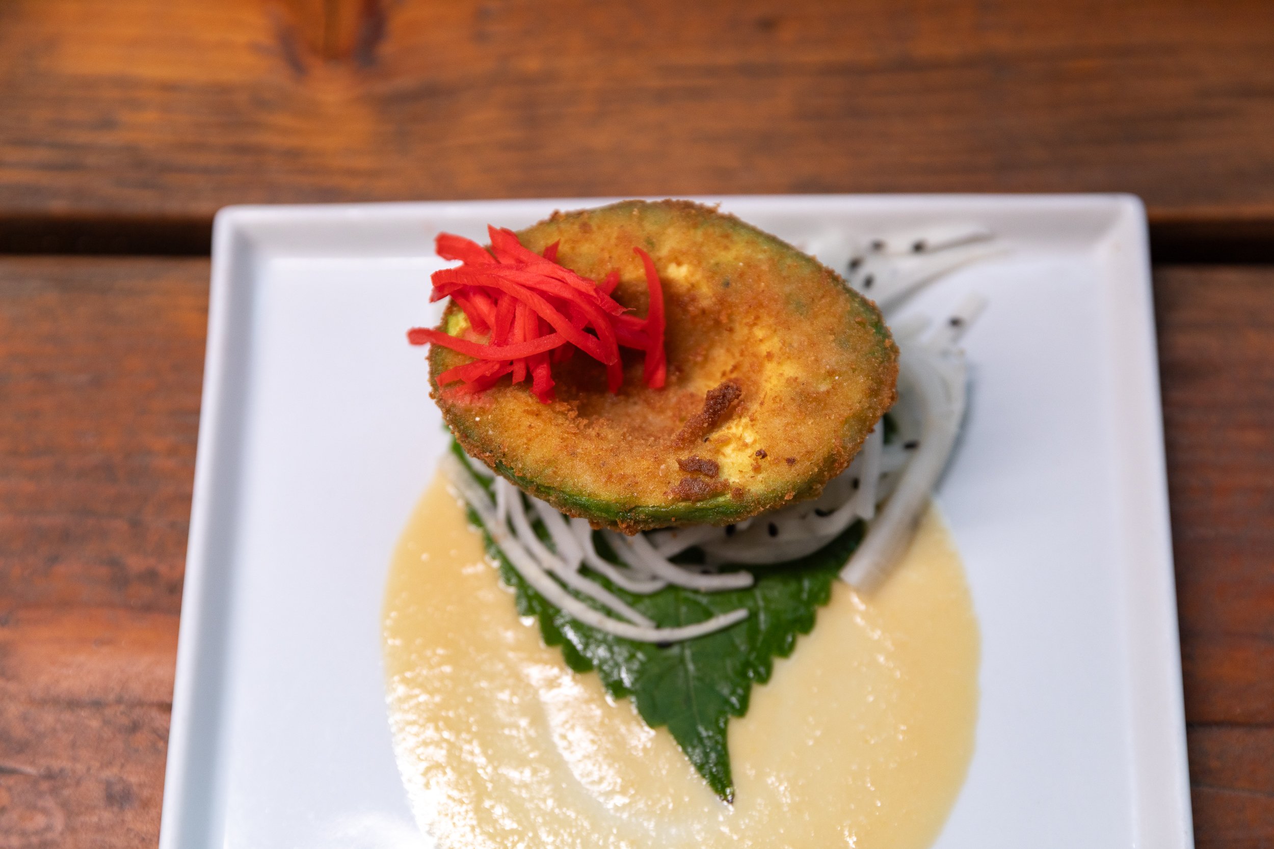 Plated appetizer with a bright garnish over a creamy sauce, catered by Bacchus
