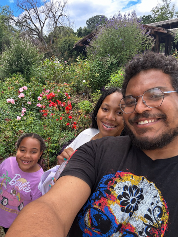 Jazzmin and Sean and Nova taking a family selfie with their daughter among colorful flowers