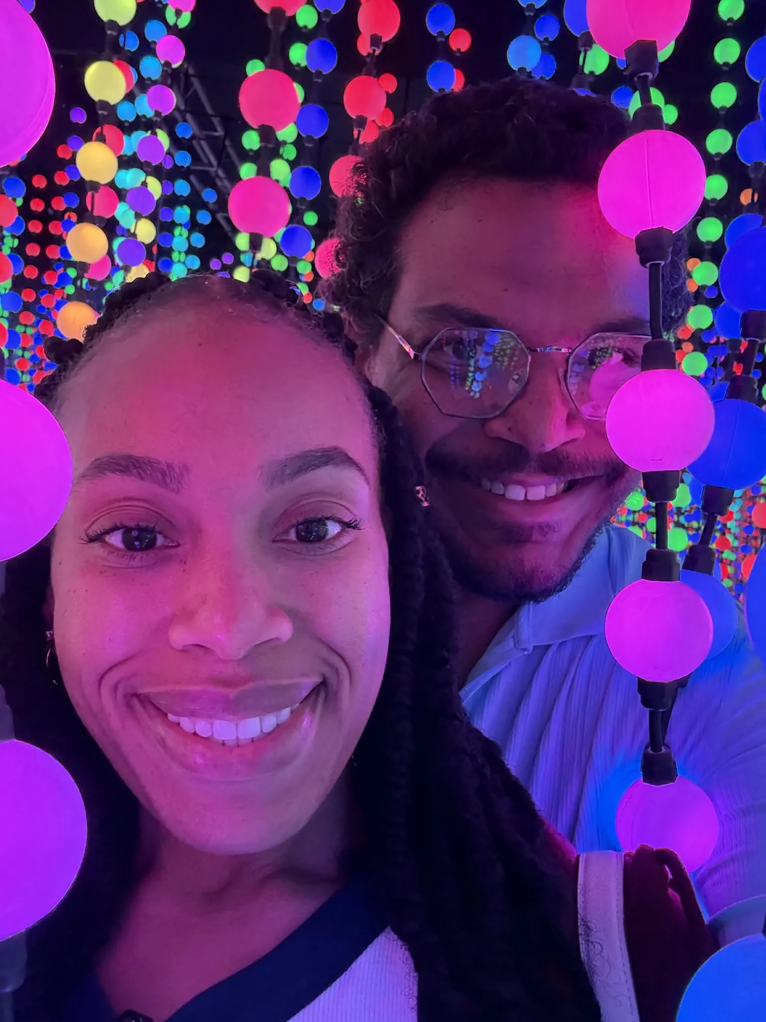 Jazzmin and Sean smiling together surrounded by colorful glowing lights