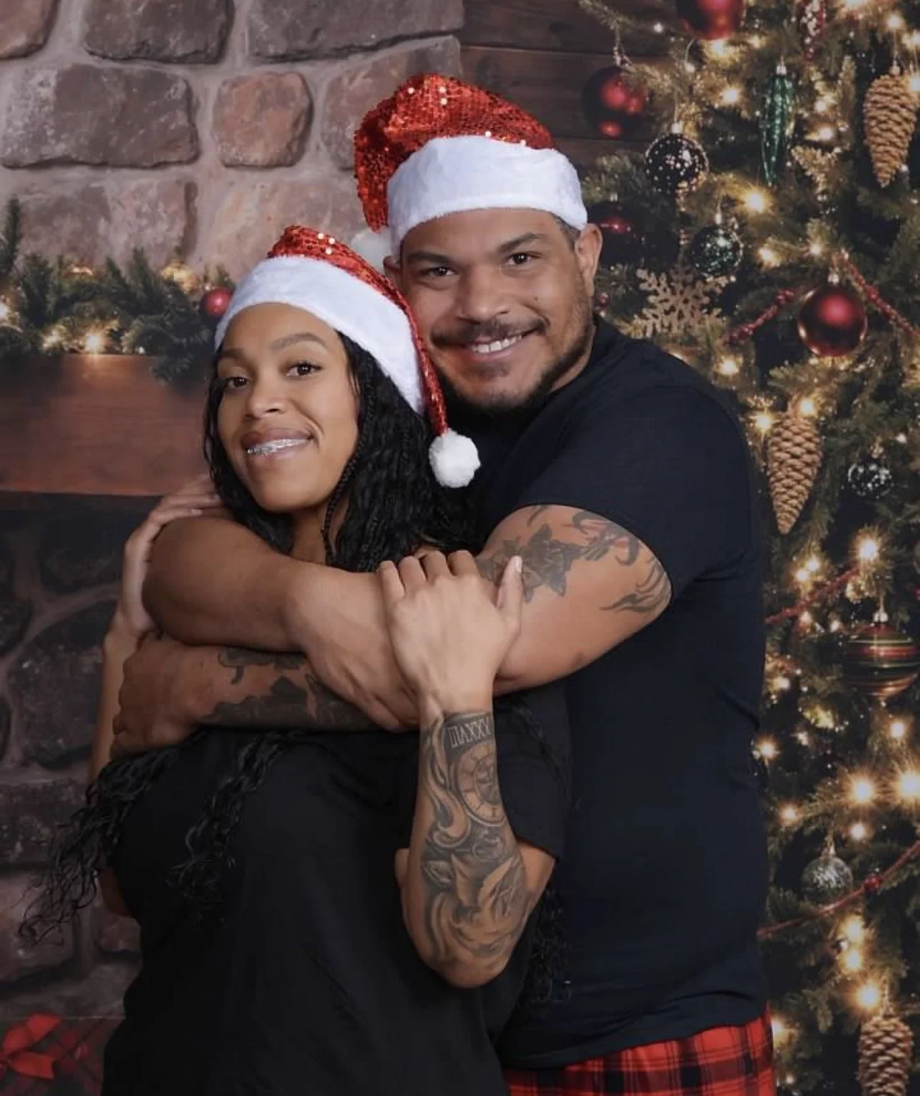 Jazzmin and Sean hugging together in front of a decorated Christmas tree