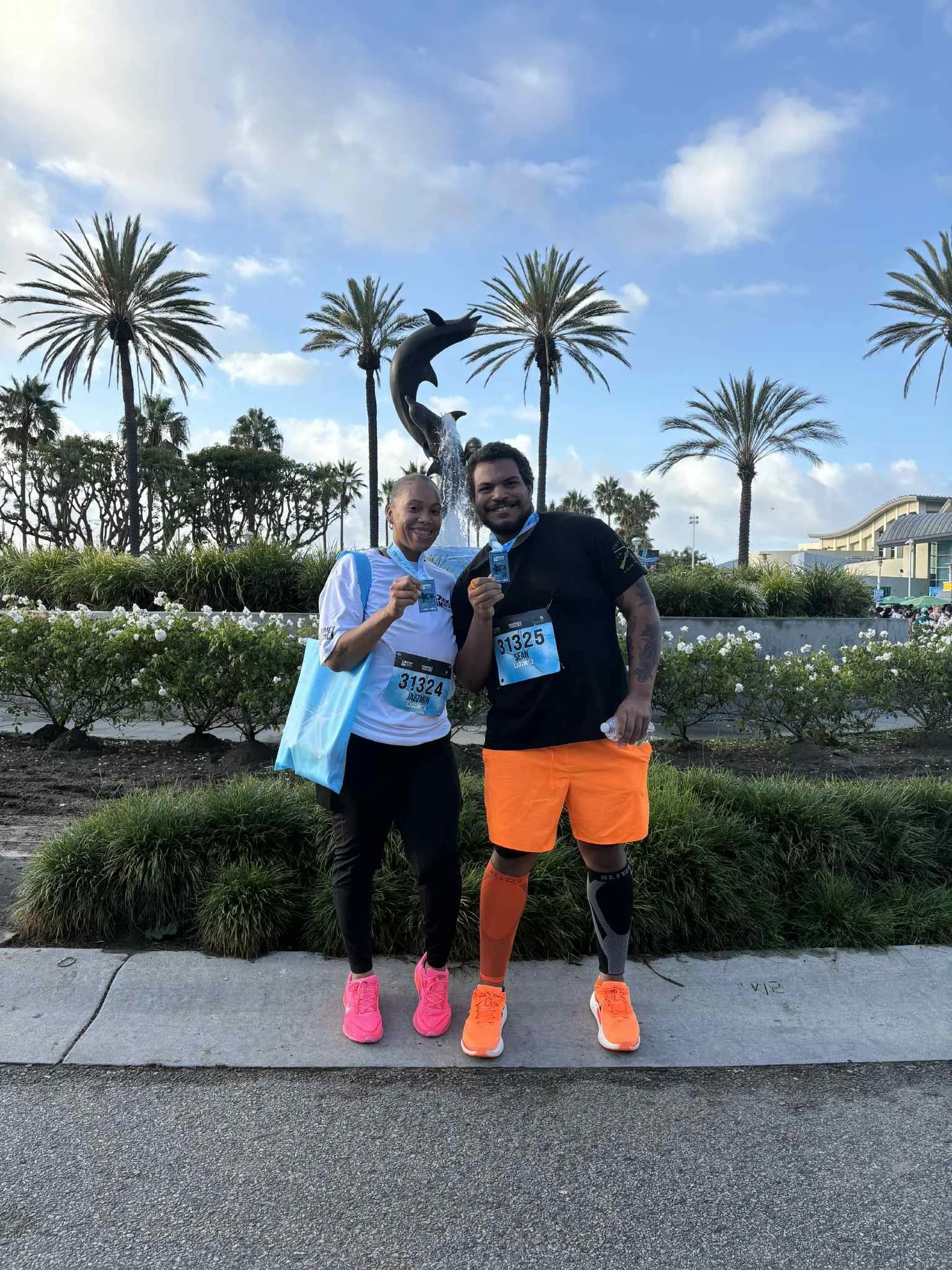 Jazzmin and Sean posing together with their race medals after completing a run at the long beach aquarium. 5k run, nike