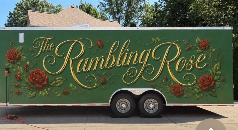 Green trailer with decorative text 'The Rambling Rose' and illustrations of red roses and green leaves.