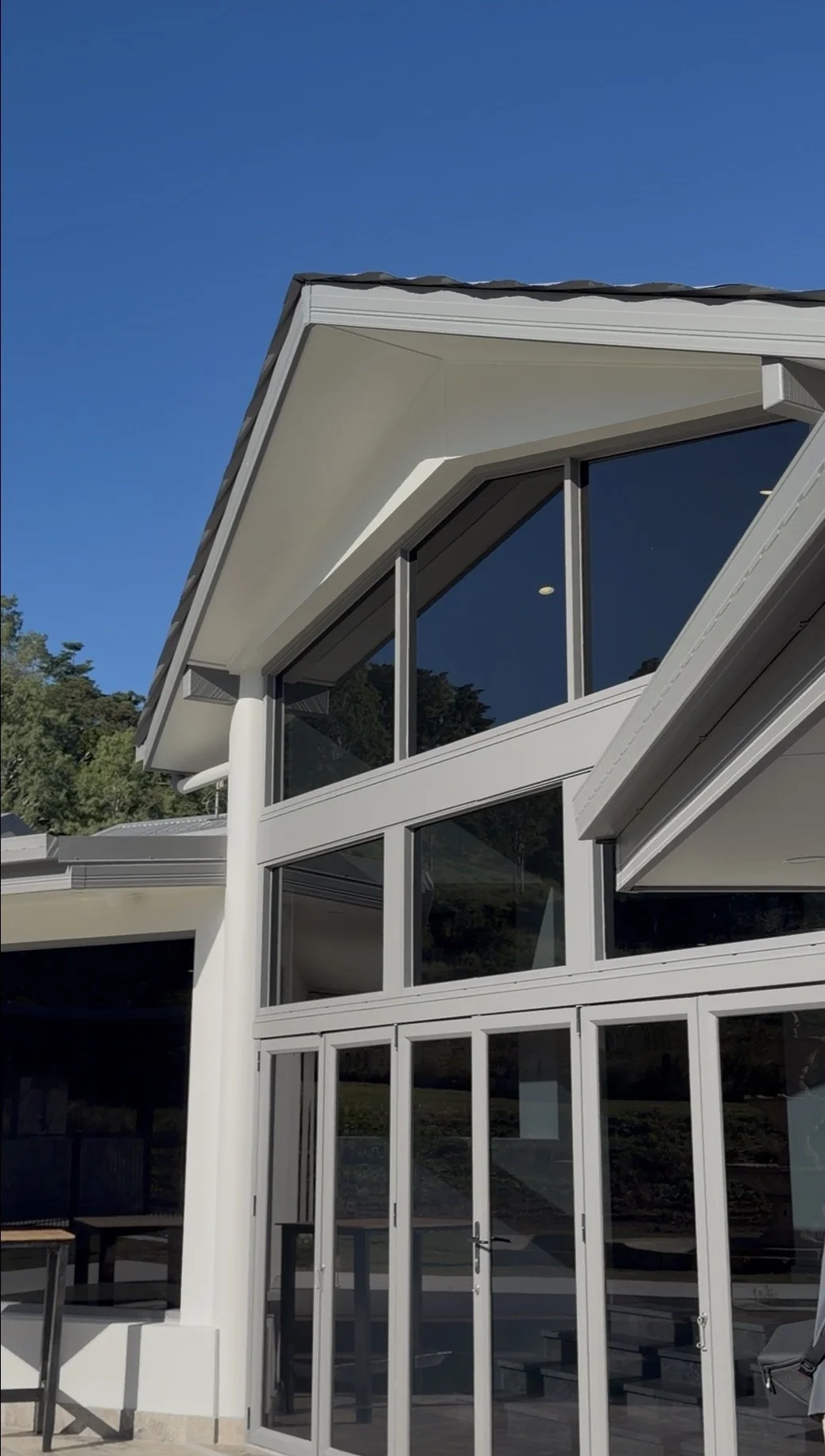 Modern house with large glass windows and a sloped roof under a clear blue sky.