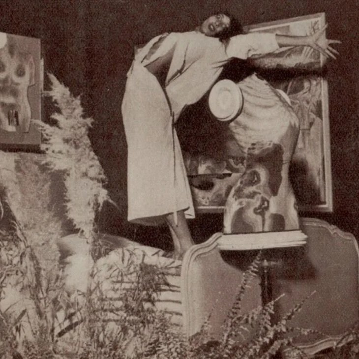 A woman placing a small Santa Claus figurine on a table, surrounded by Christmas decorations, with a large dog portrait in the background.