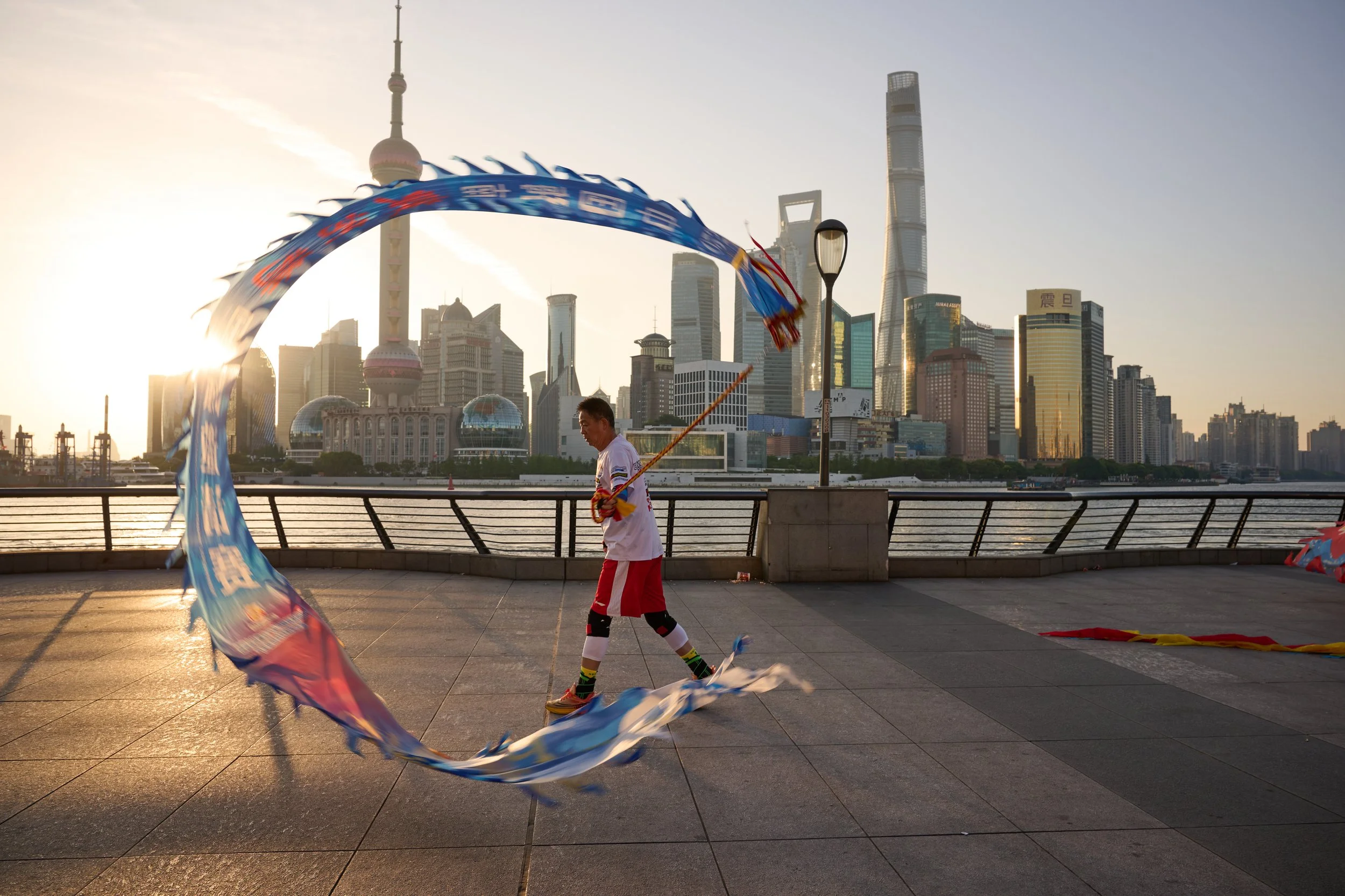 A man in Shanghai twirling a kite at the Bund in good light.  Nikon ZF 26mm