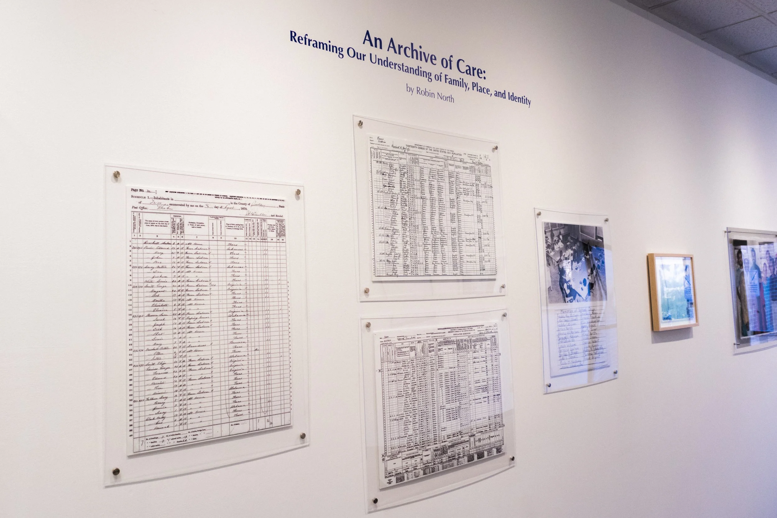 Exhibition in the Sheehan Gallery at Whitman College, wall displaying historical documents, including census records and photographs, titled 'An Archive of Care: Reframing Our Understanding of Family, Place, and Identity' by Robin North.