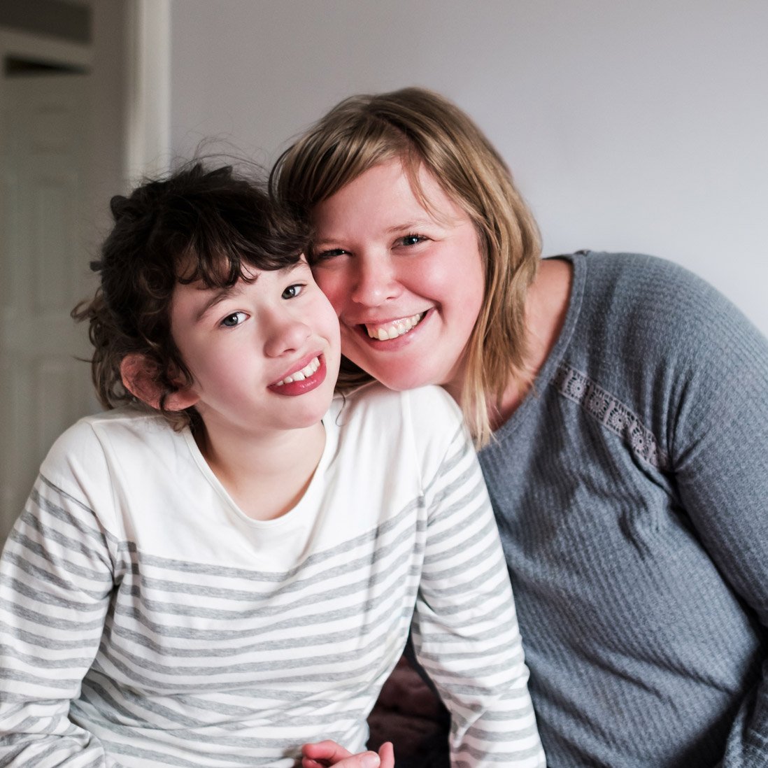 A portrait of a disabled child cheek to cheek with a parent