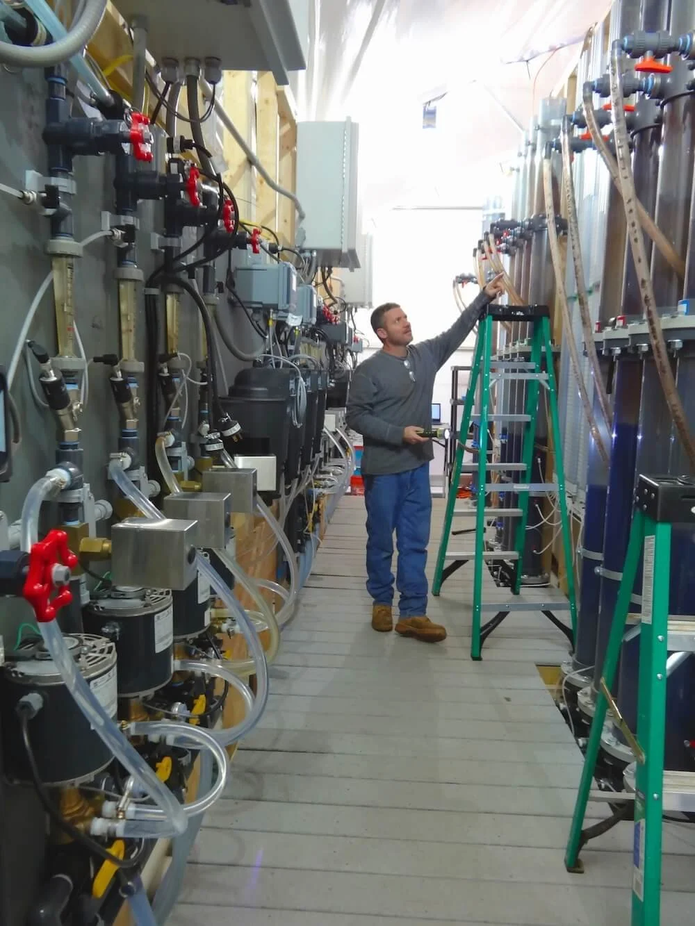 An employee checking on the pilot study water treatment testing setup in Providence, RI to ensure all instruments and pumps are functioning properly.