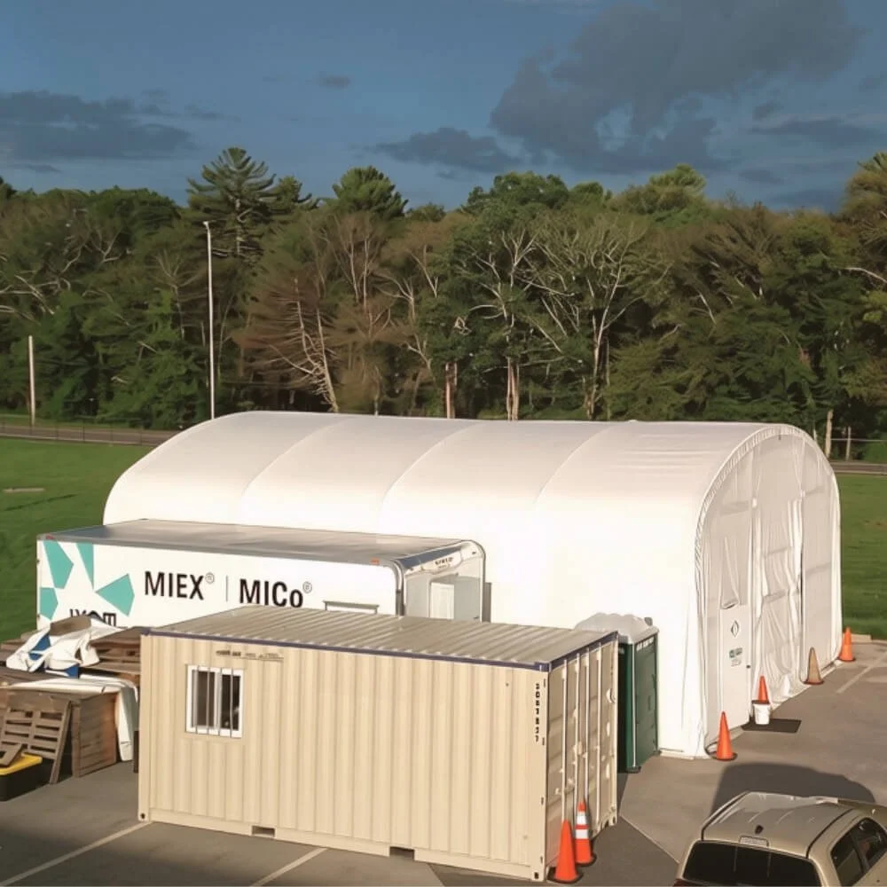A white tent and additional trailers being used to house the wastewater treatment pilot testing equipment.