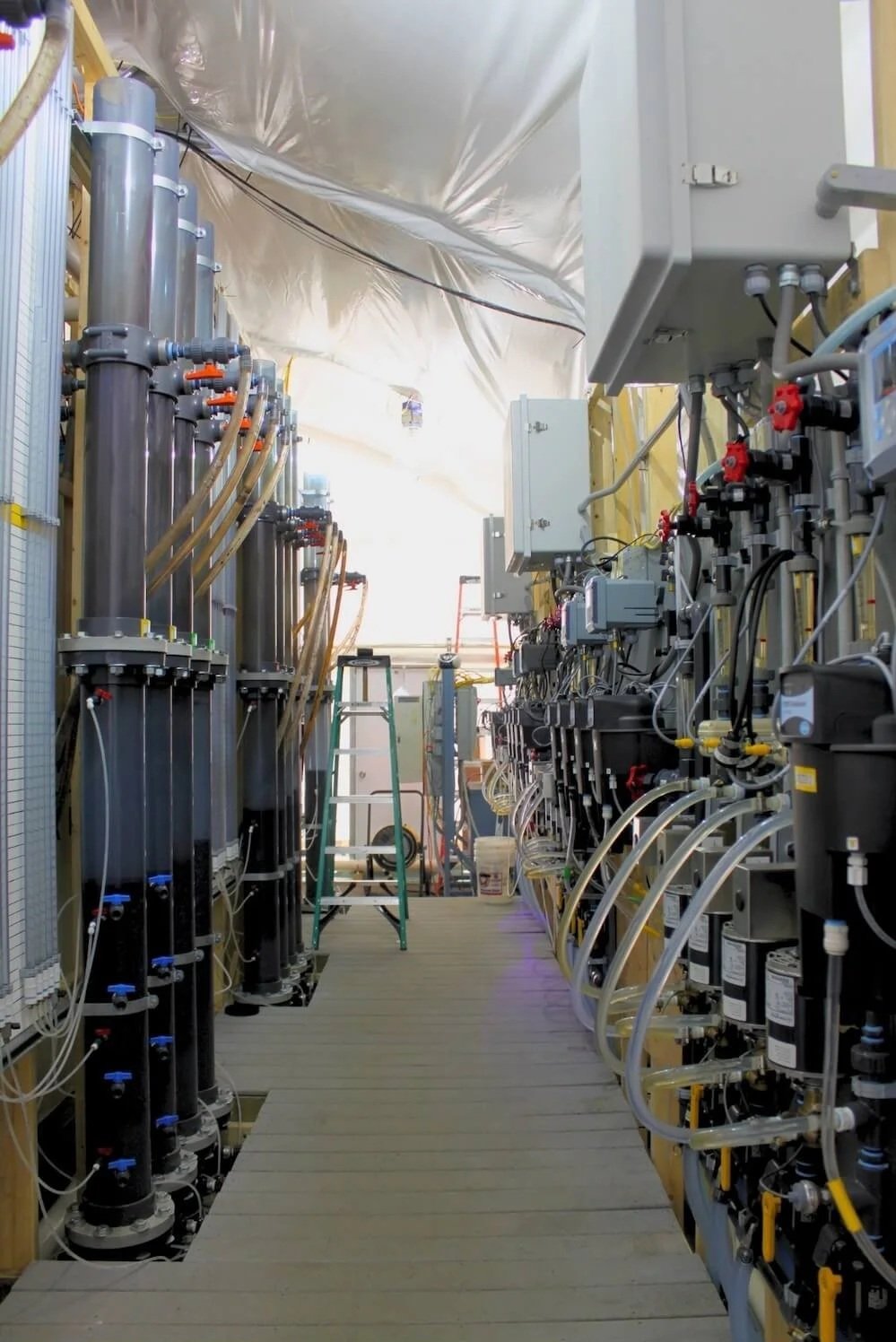 Pilot testing equipment setup inside a white tent to conduct a pilot study for wastewater treatment plant.