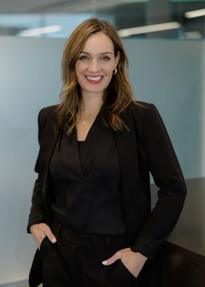 Woman with brown hair in business attire smiling in an office.