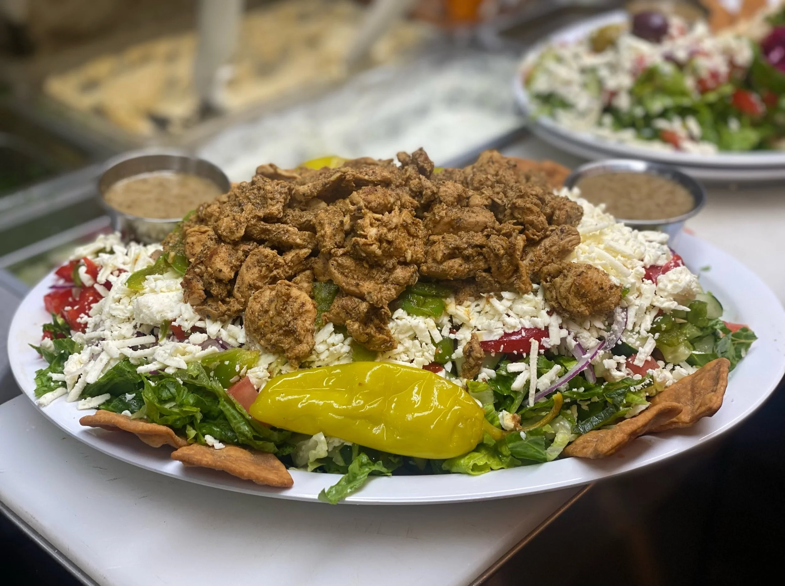 A plate of taco salad with shredded cheese, lettuce, tomatoes, ground beef, yellow peppers, and crispy taco shell