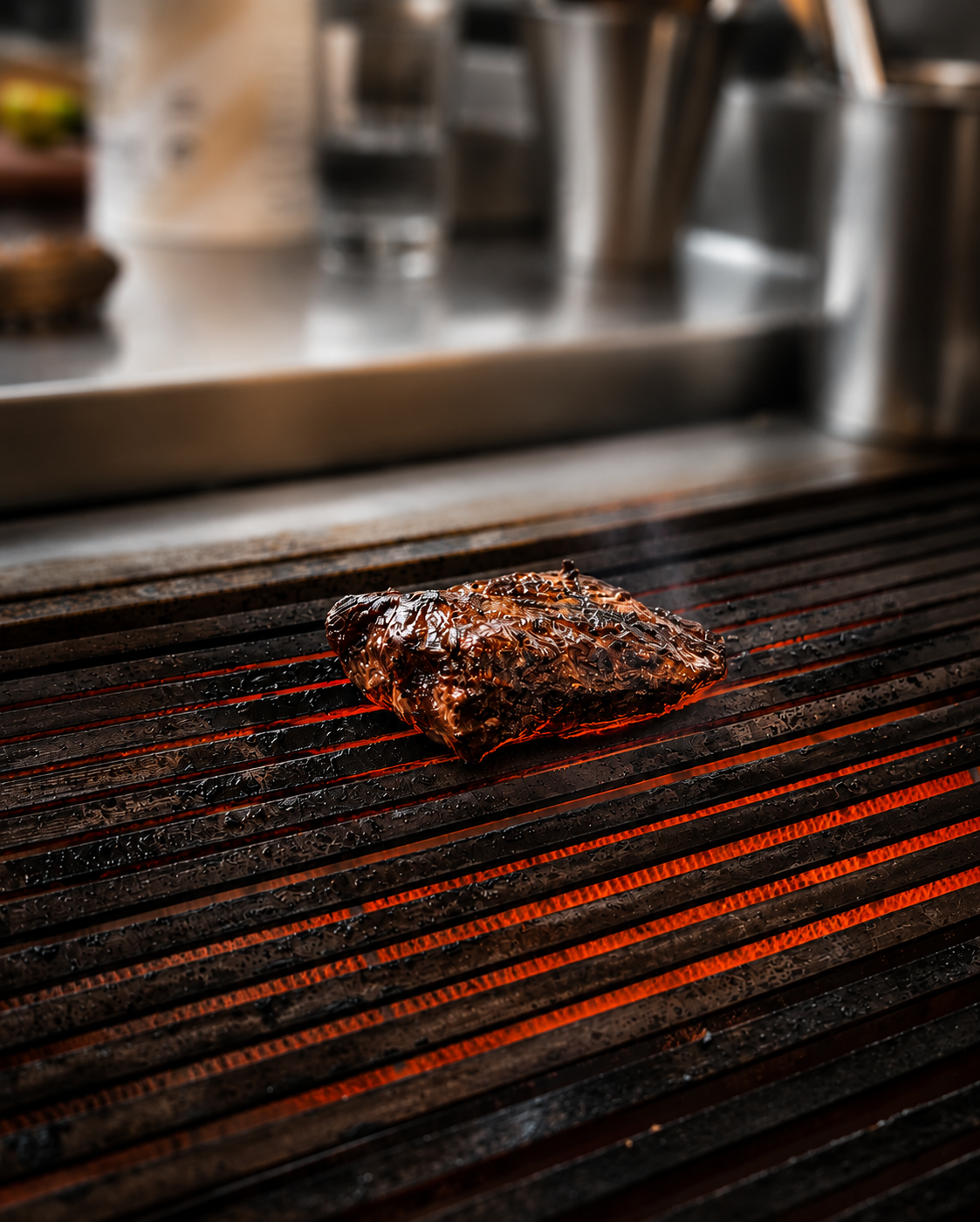 Asado. A piece of marinated meat cooking on a grill over glowing red heat.