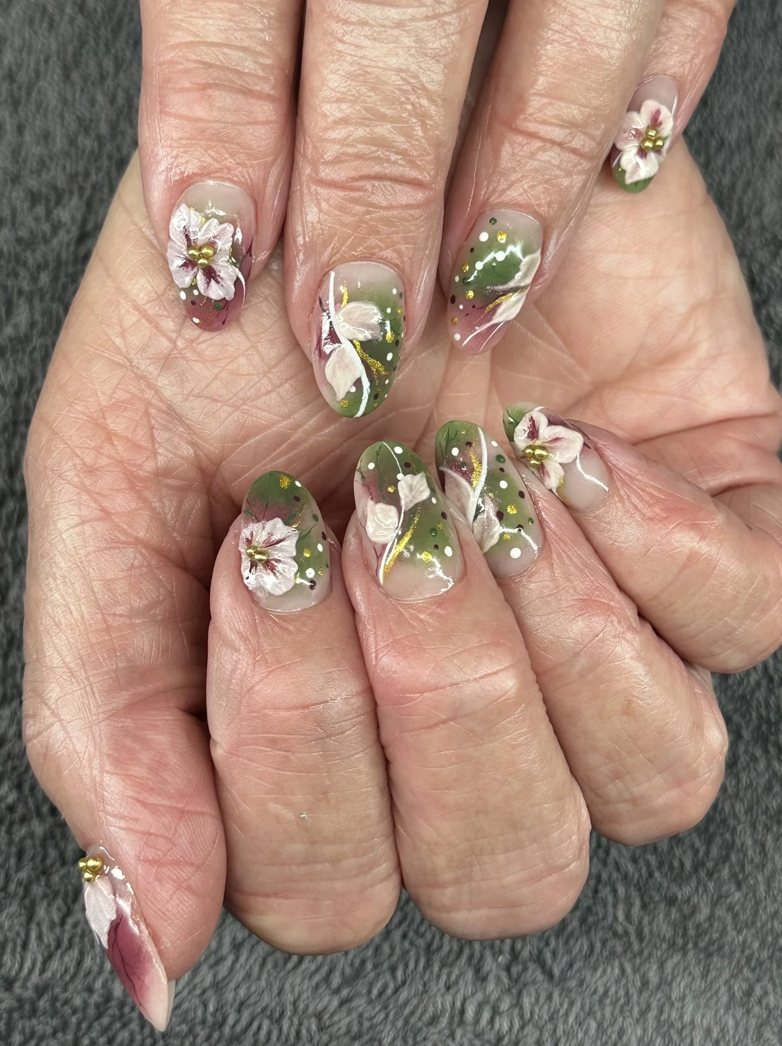 “Green floral nail art with hand-painted white flowers and gold details, created by Roses Kustom Worx in Taupō.”