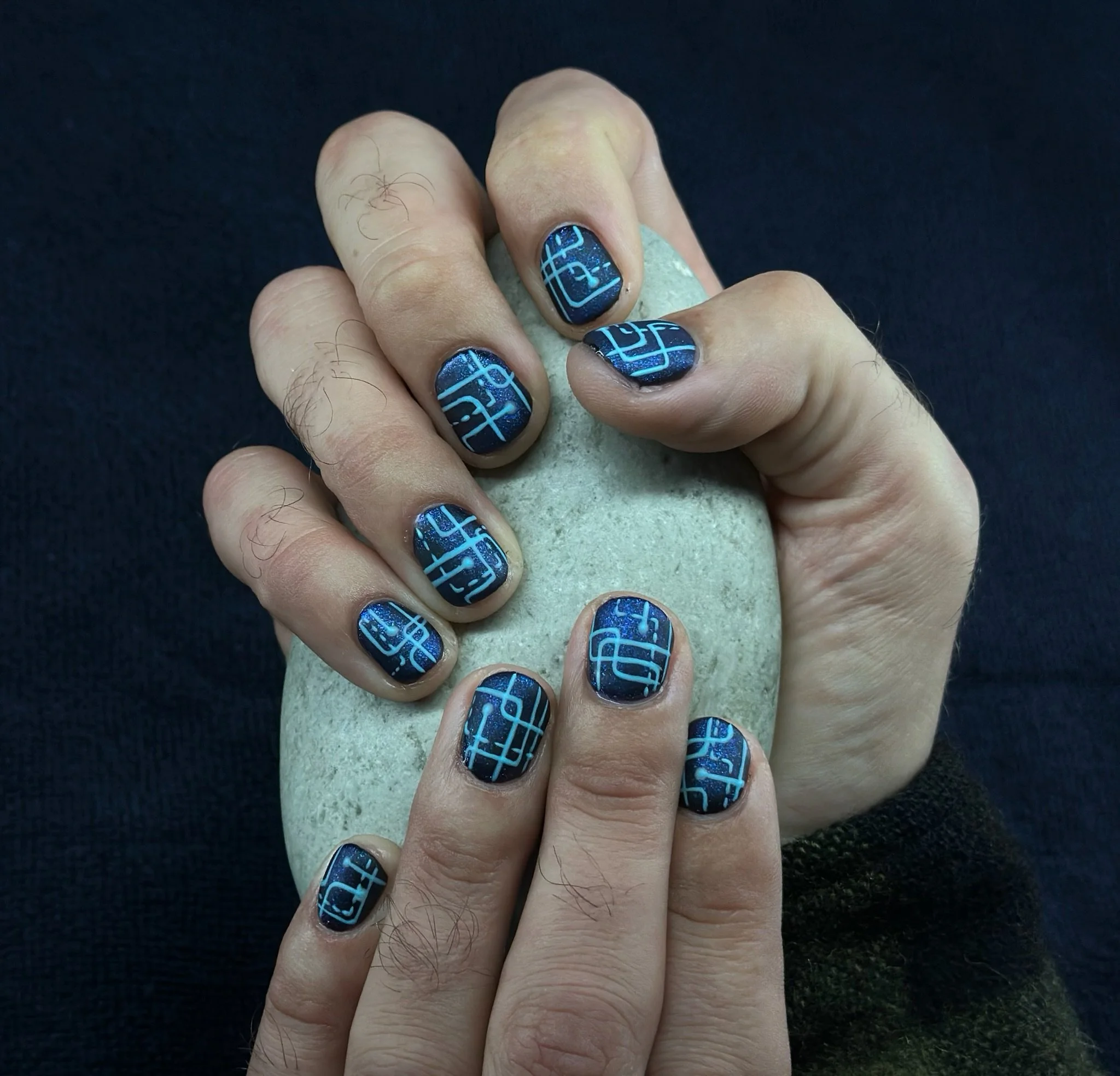 “Blue and black nail art featuring abstract geometric patterns, created by Roses Kustom Worx in Taupō.”