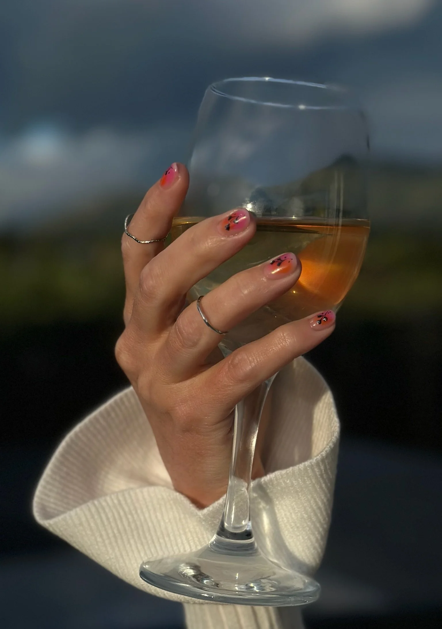 “Warm-toned nail art photographed holding a glass outdoors, created by Roses Kustom Worx in Taupō.”
